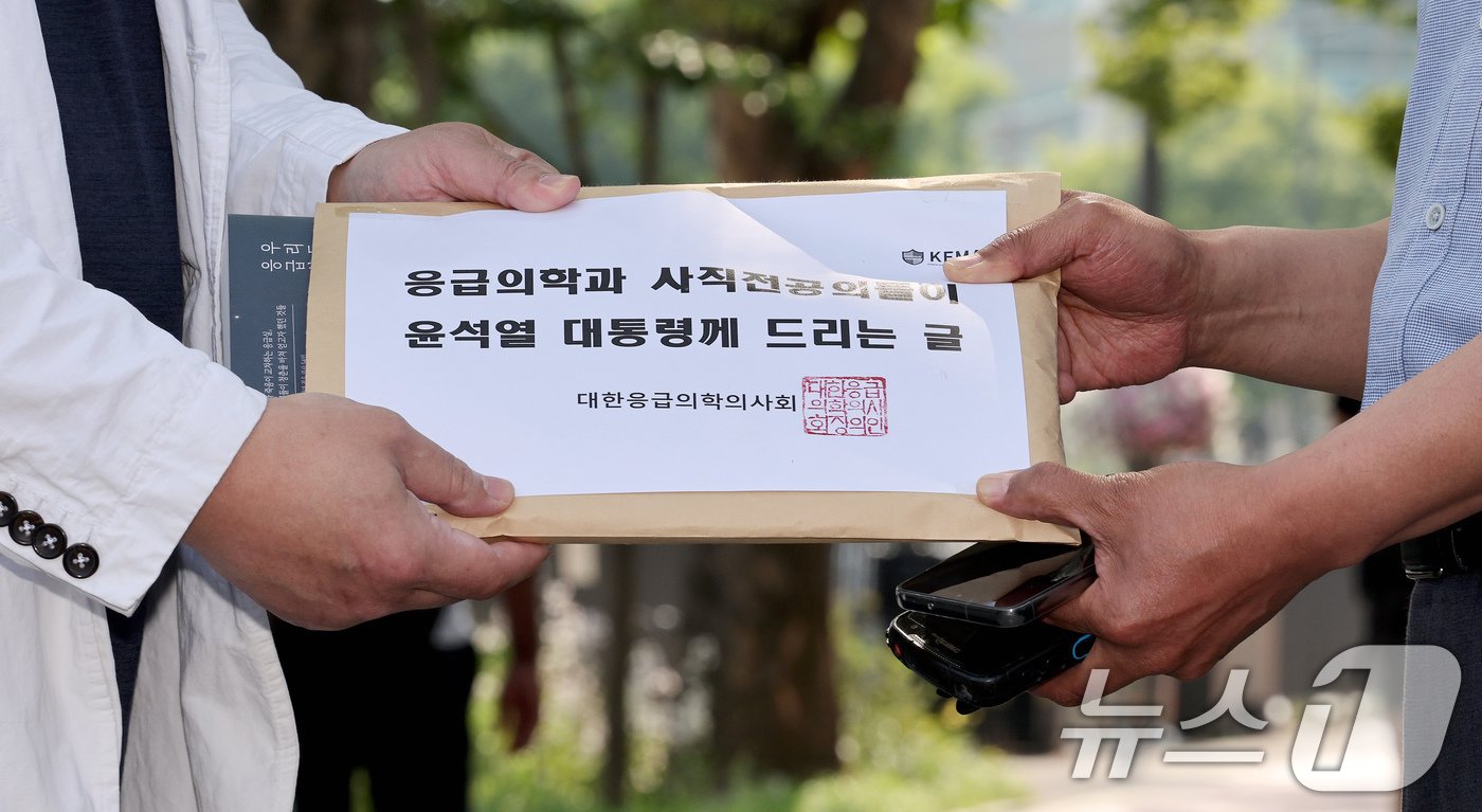 본문 이미지 - 이형민 대한응급의학의사회 회장(왼쪽)이 22일 오후 서울 용산구 대통령실 앞에서 대통령실 관계자에게 '응급의학과 사직전공의들이 윤석열 대통령께 드리는 글'과 '응급실, 우리들의 24시간'책을 전달하고 있다. 2024.5.22/뉴스1 ⓒ News1 장수영 기자