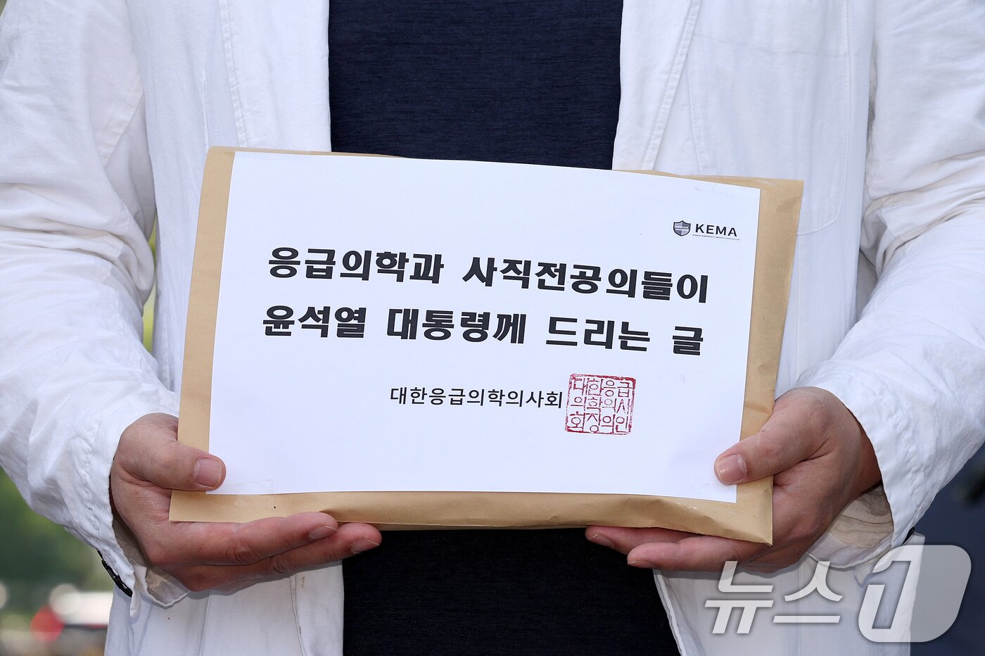 본문 이미지 - 이형민 대한응급의학의사회 회장이 22일 오후 서울 용산구 대통령실 앞에서 윤 대통령에게 전달할 '응급의학과 사직전공의들이 윤석열 대통령께 드리는 글'을 들어보이고 있다. 2024.5.22/뉴스1 ⓒ News1 장수영 기자