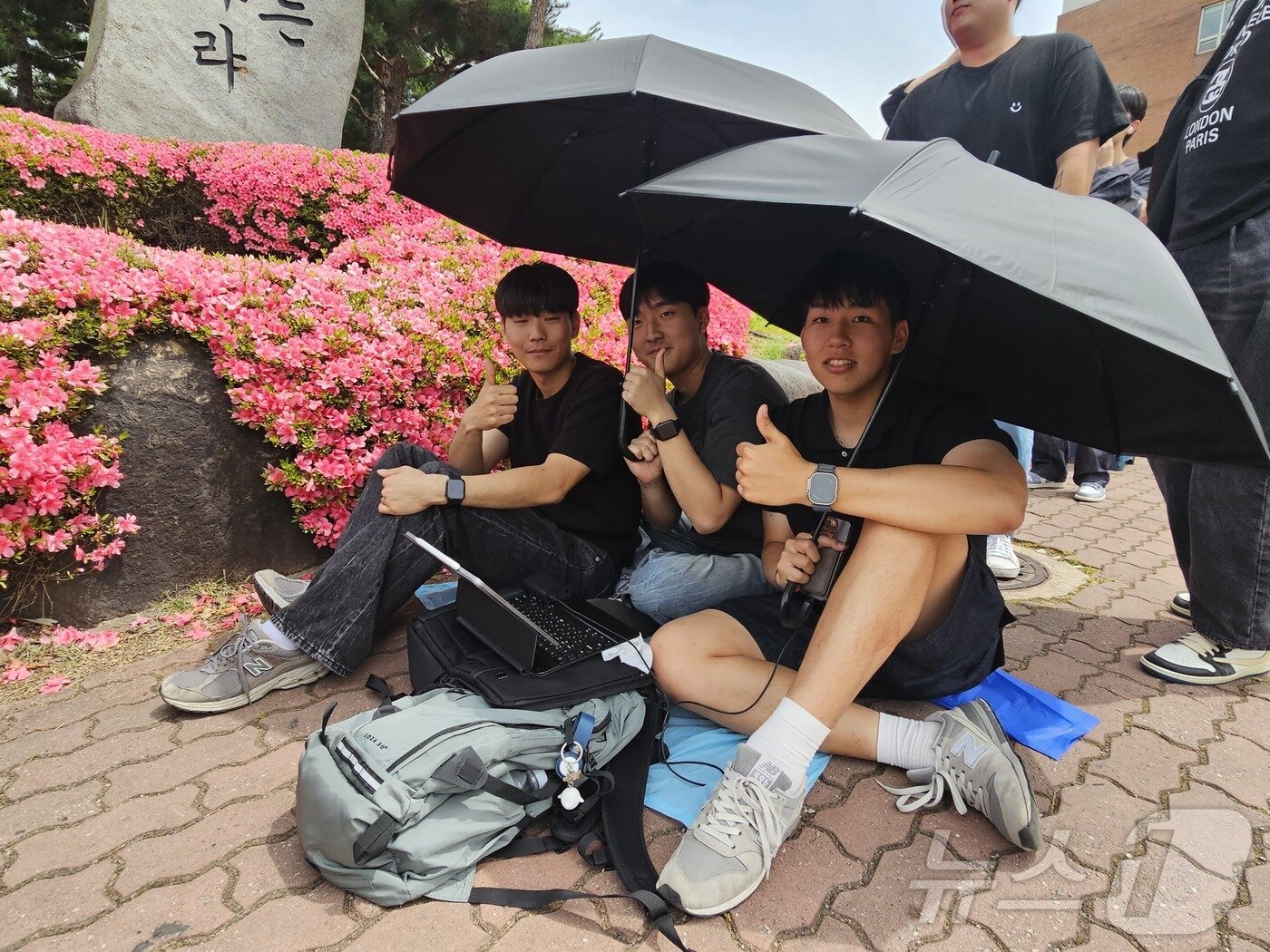 본문 이미지 - 27일 오후 조선대학교에서 이번학기 복학생 박모씨(23·오른쪽)가 중학교 동창들과 우산으로 햇빛을 가린채 뉴진스 뮤직비디오를 보며 입장을 기다리고 있다.2024.5.27./뉴스1 ⓒ News1 서충섭 기자