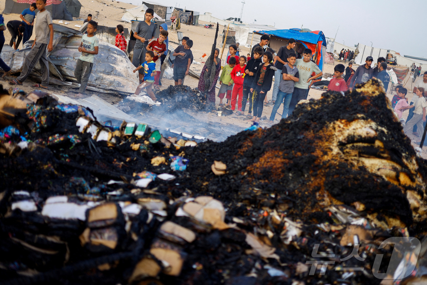 (라파 로이터=뉴스1) 박재하 기자 = 27일(현지시간) 가자지구 최남단 라파의 텔 알술탄 난민촌에서 피란민들이 이스라엘군 공습에 불타버린 구호품을 쳐다보고 있다. 이 공습으로 최 …