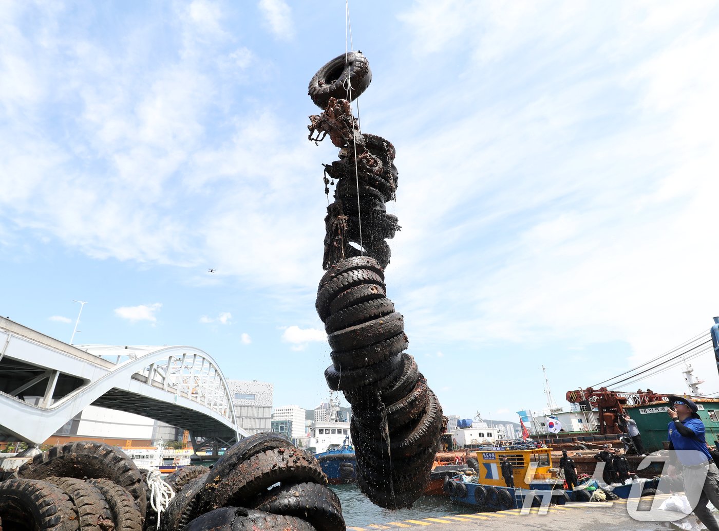 본문 이미지 - 제29회 바다의 날을 사흘 앞둔 28일 부산 영도구 봉래동 물양장에서 중앙해양특수구조단, 한국해양구조협회 전문 다이버 등이 바닷속에 버러져 있던 폐타이어와 오토바이를 크레인을 동원해 육지로 끌어올리고 있다. 부산시와 부산해양경찰서가 공동 주관한 이번 해양환경정화 활동 행사에는 영도구, 해양환경공단, 부산항만공사, 한국해양구조협회, 민간 기업·협회 등 19개 기관·단체와 시민 등 160여 명이 참여했다. 2024.5.28/뉴스1 ⓒ News1 윤일지 기자