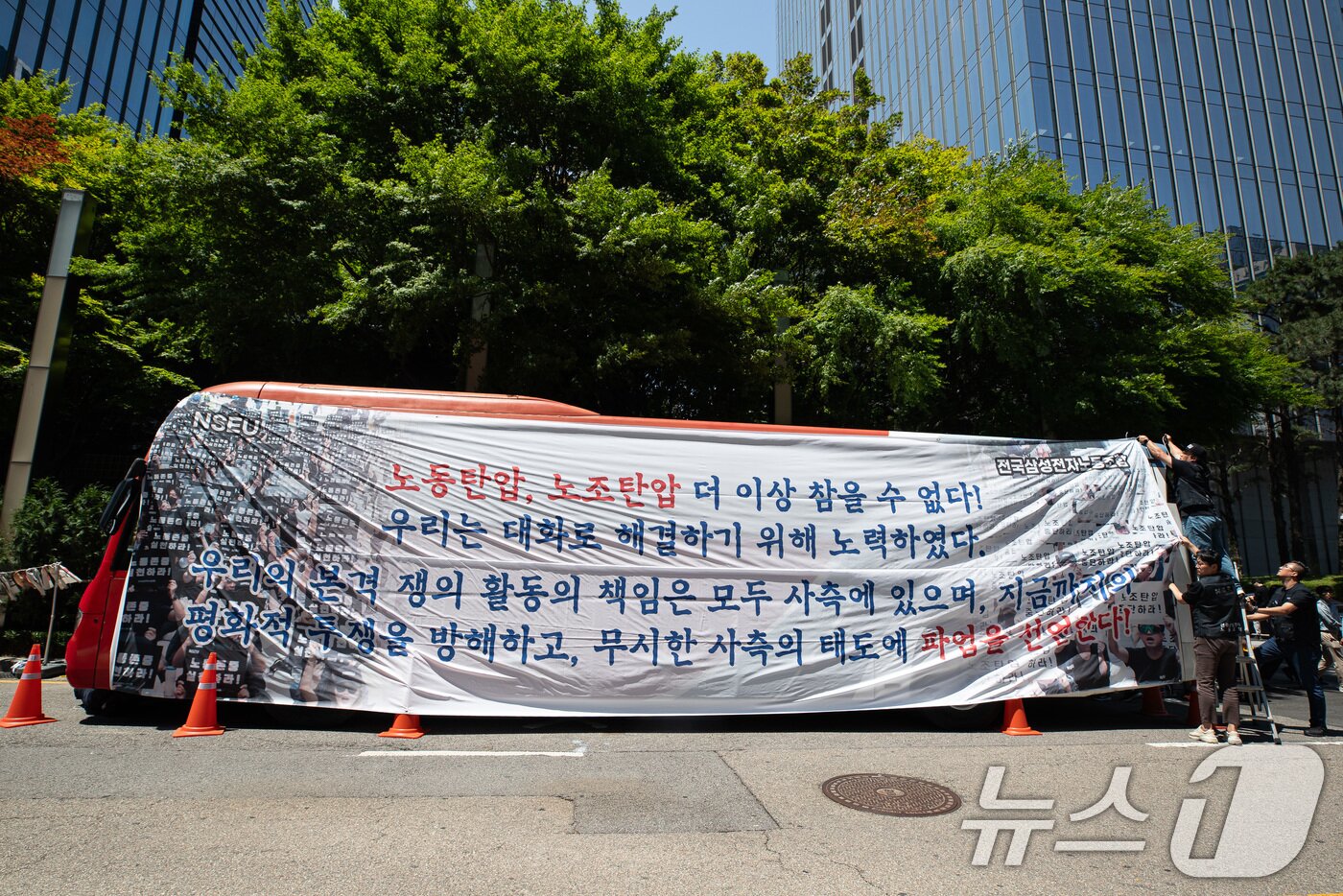 본문 이미지 - 전국삼성전자노동조합 조합원들이 29일 서울 강남구 삼성전자 서초사옥 앞에서 파업 선언 기자회견을 마친 후 대형버스에 현수막을 매다는 퍼포먼스를 하고 있다. 2024.5.29/뉴스1 ⓒ News1 유승관 기자