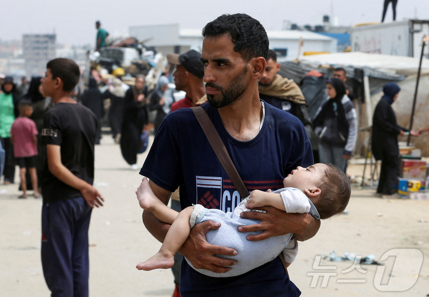 (라파 로이터=뉴스1) 권진영 기자 = 28일(현지시간) 가자지구 최남단 라파에서 한 팔레스타인 남성이 아기를 안고 이스라엘의 지상작전을 피해 대피하고 있다. 2024.05.28/ …