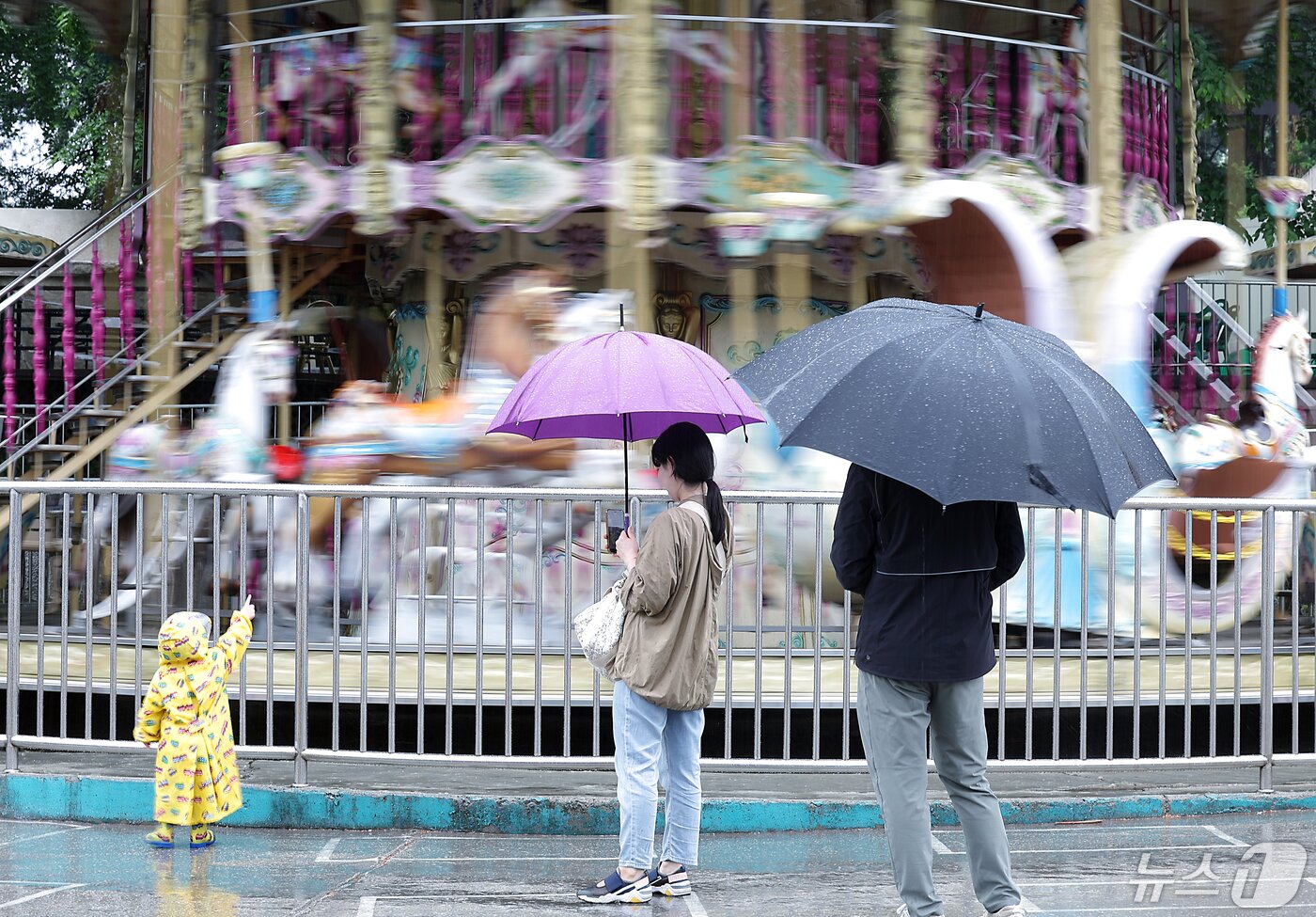 본문 이미지 - 전국적으로 비가 내리고 있는 어린이날인 5일 서울 광진구 능동 어린이대공원을 찾은 가족단위 방문객들이 한산한 놀이공원 내 회전목마를 구경하고 있다. 2024.5.5/뉴스1 ⓒ News1 박정호 기자