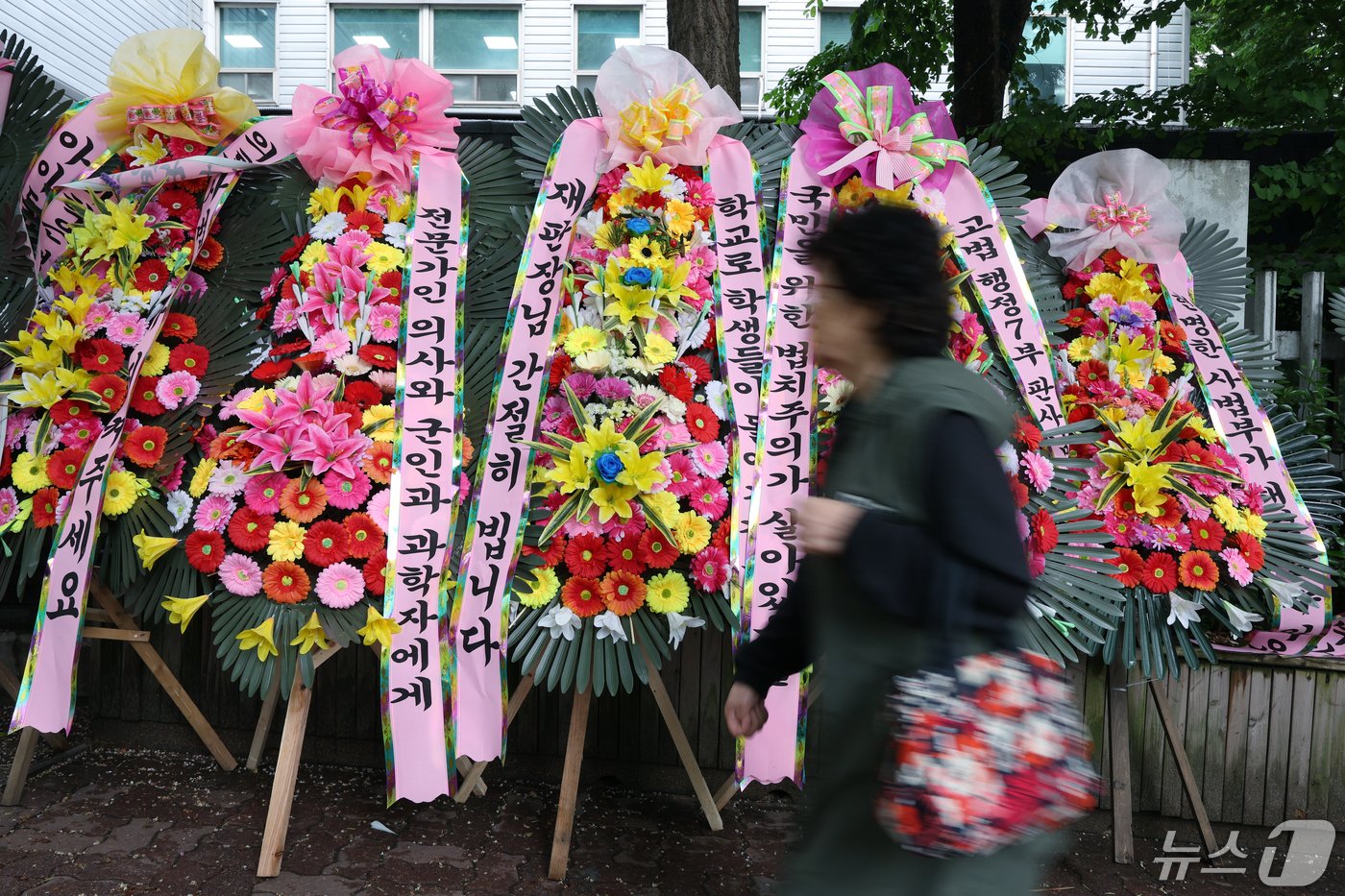 7일 서울 서초구 서초중앙로 서울중앙지방법원과 서울고등법원 등이 위치한 서울법원종합청사 외부 인도에 서울고법 행정7부 재판부를 응원하는 화환이 놓여 지나는 시민들의 눈길을 끌고 있다. 의대교수·전공의·의대생·수험생 등이 신청한 의과대학 정원 증원 집행정지를 심리하고 있는 서울고법 행정7부&#40;부장판사 구회근&#41;는 정부 측에 &#39;증원 규모를 2000명으로 정한 과학적 근거&#39;를 내라고 요구했으며, 또 집행정지 항고심 결정 전까지 정원 최종 승인을 하지 말라고 권고했다. 2024.5.7/뉴스1 ⓒ News1 박정호 기자