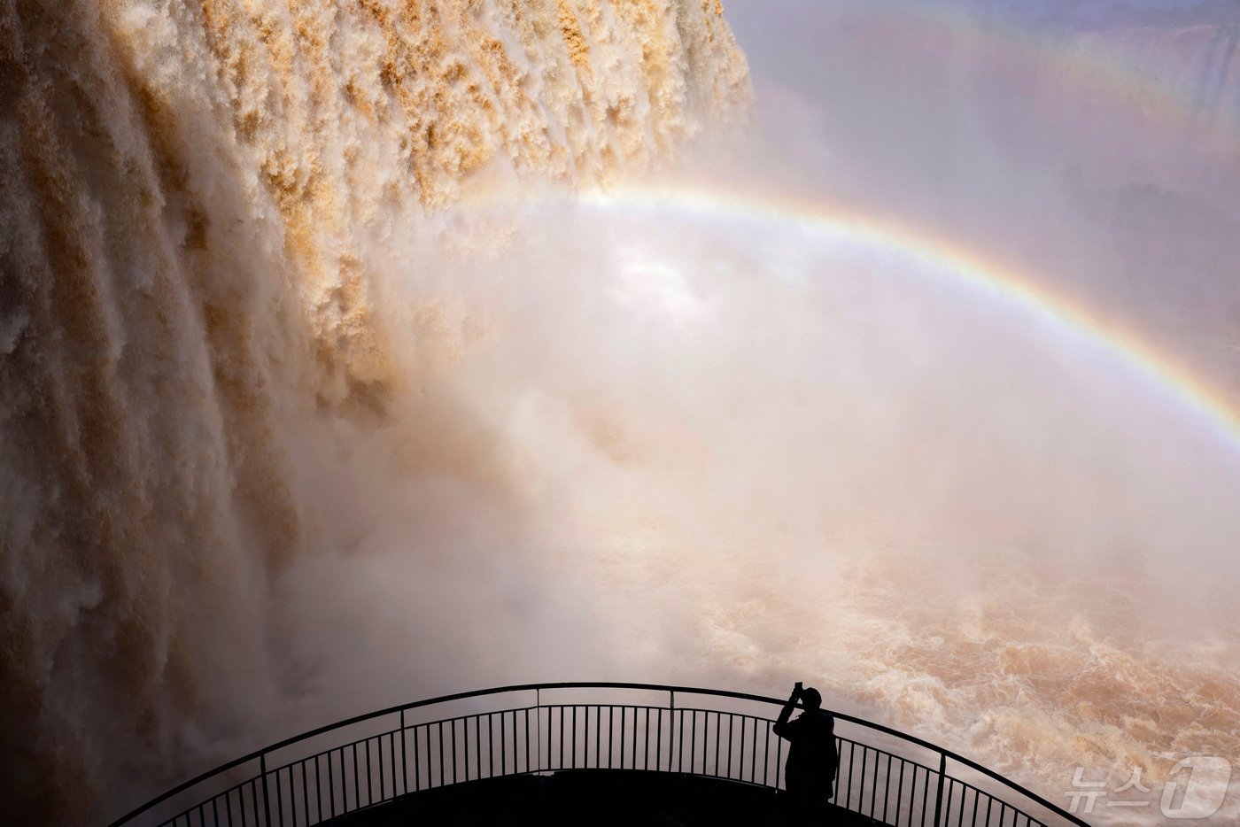 본문 이미지 - 이구아수 폭포가 물이 불어 장관을 이루자 한 관광객이 사진을 찍고 있다. 무지개는 덤이다. ⓒ 로이터=뉴스1 ⓒ News1 박형기 기자