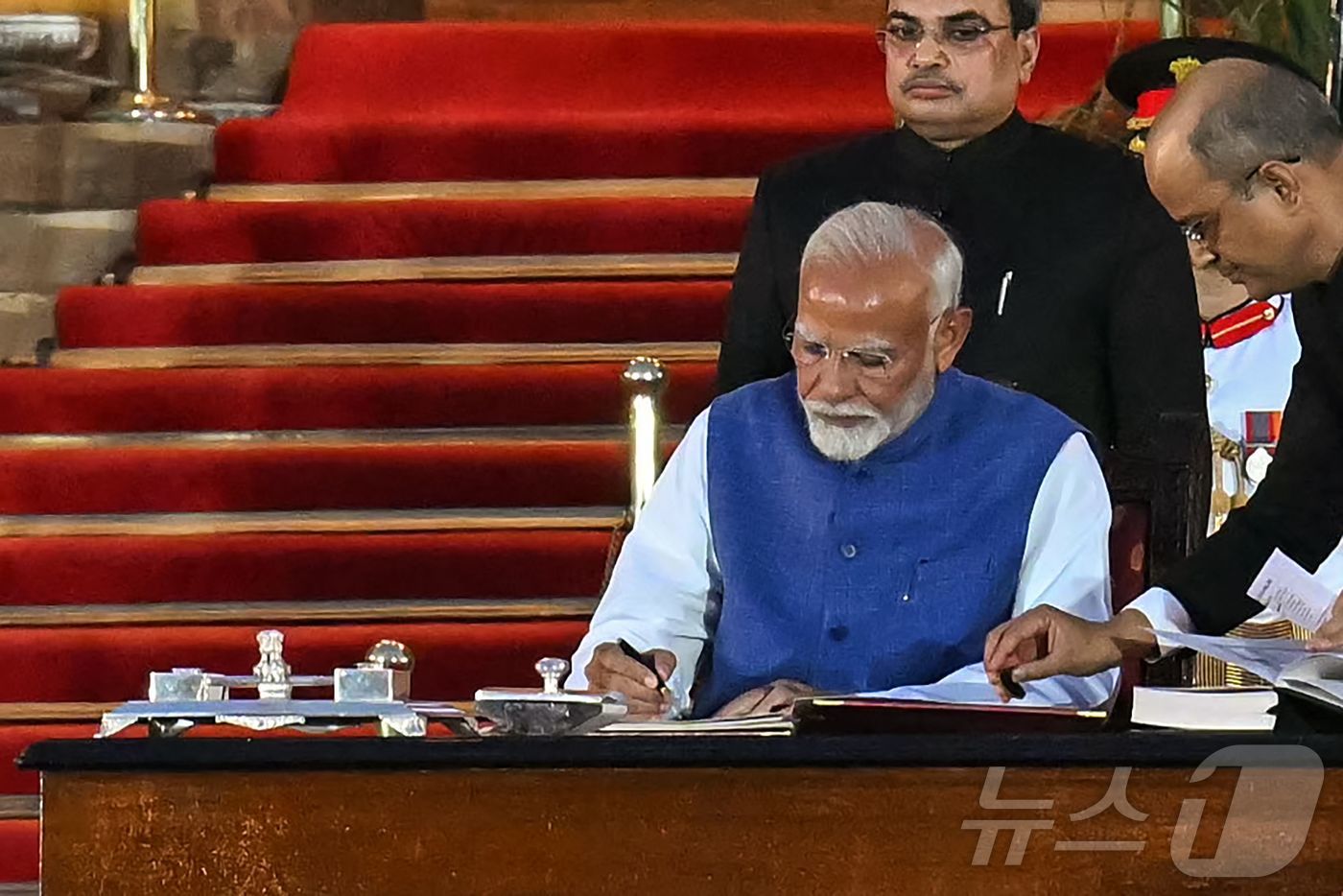 (뉴델리 AFP=뉴스1) 우동명 기자 = 나렌드라 모디 인도 총리가 9일(현지시간) 뉴델리 대통령 궁에서 세 번째 임기를 시작하는 총리 취임식을 마친 뒤 서명을 하고 있다. 202 …