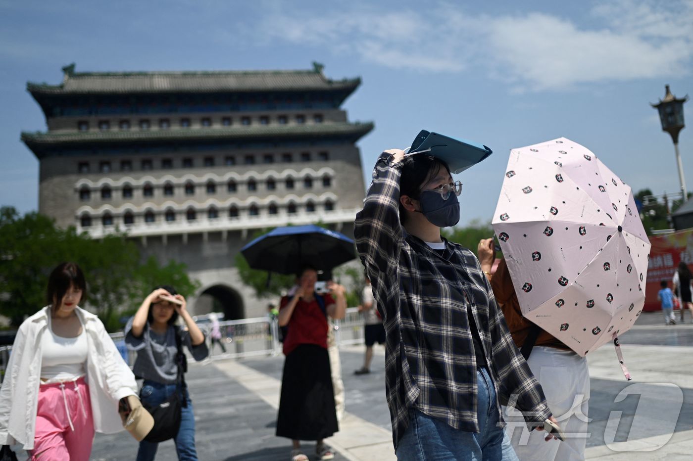 (AFP=뉴스1) 권영미 기자 = 11일 중국인들이 베이징의 한 거리를 햇빛을 가려가며 걷고 있다. 2024.06.11.ⓒ AFP=뉴스1