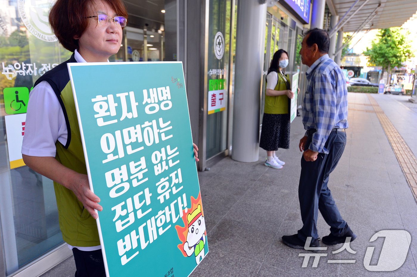 본문 이미지 - 의사들이 집단 휴진을 예고한 18일 오전 광주 동구 전남대학교병원 입구에서 보건의료노조 관계자가 '명분 없는 집단 휴진 반대' 피켓을 들고 있다. 2024.6.18/뉴스1 ⓒ News1 이승현 기자