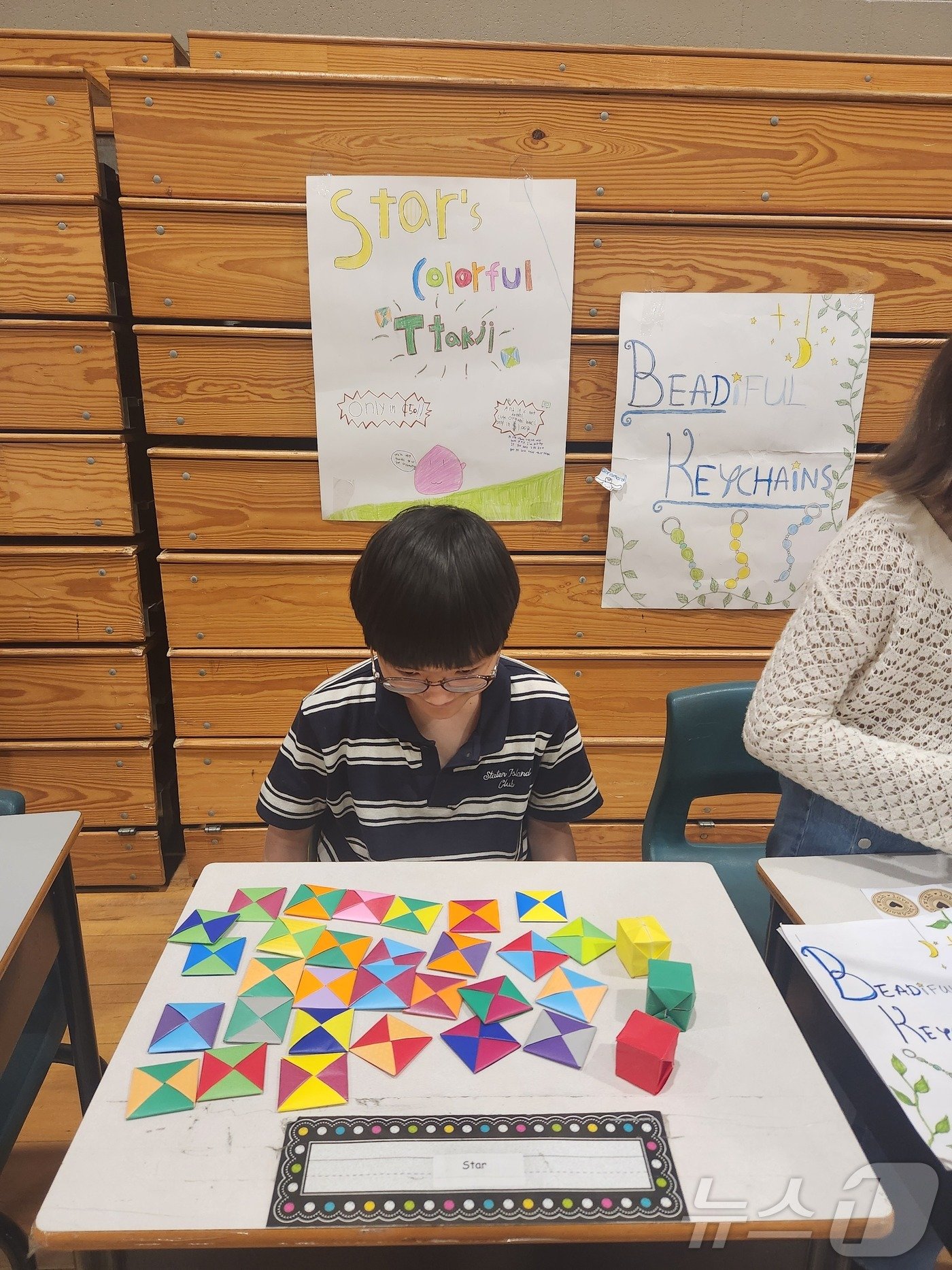 본문 이미지 - 학기를 마칠 무렵, 아들이 직접 만든 K-딱지를 판매하고 있다. 색이 영롱한 한국식 색종이로 칼각을 맞춰 접었다. 이날 장사는 목표 수익 60달러를 달성했다. 2024.06.04/ ⓒ 뉴스1 김남희 통신원