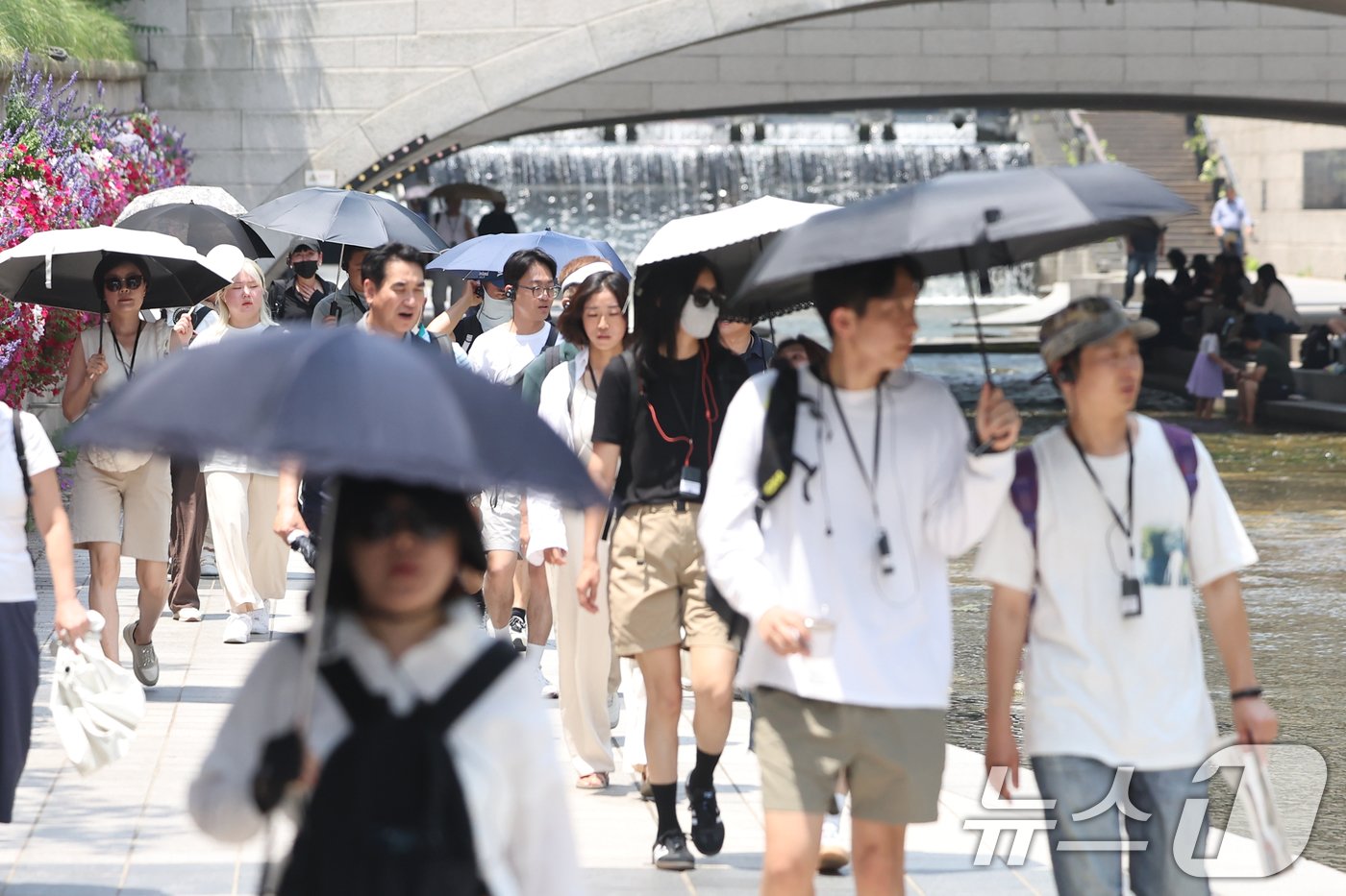 본문 이미지 - 서울 지역 낮 최고 기온이 35도까지 올라 불볕더위가 찾아온 20일 서울 종로구 청계천에서 시민들이 양산을 펼쳐 따가운 햇빛을 막고 있다. 2024.6.20/뉴스1 ⓒ News1 민경석 기자