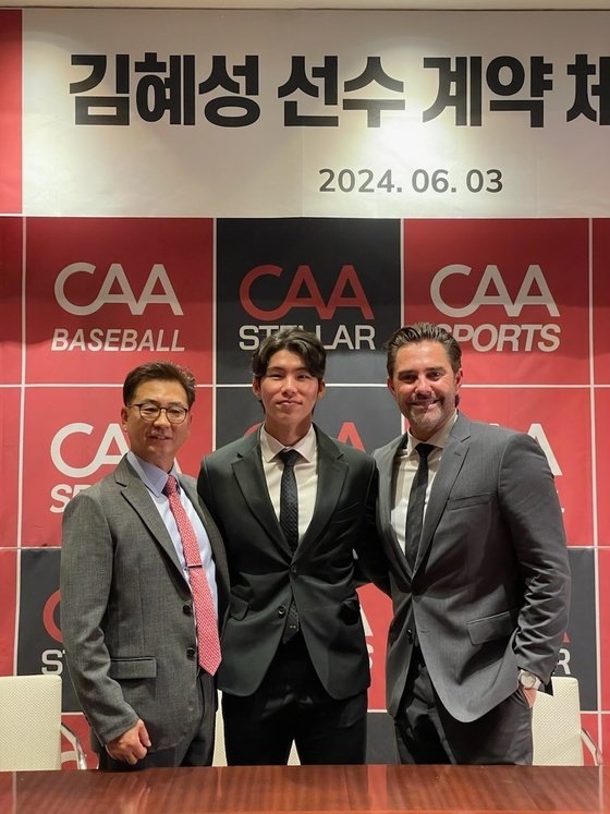 본문 이미지 - 김혜성(가운데)이 3일 서울 용산구 그랜드 하얏트 서울에서 CAA 스포츠와 계약을 체결한 뒤 기념 촬영을 하고 있다. 왼쪽은 장기영 CAA 스텔라 한국지사 대표, 오른쪽은 마이크 니키아스 CAA 스포츠 에이전트. (CAA 스텔라 제공)