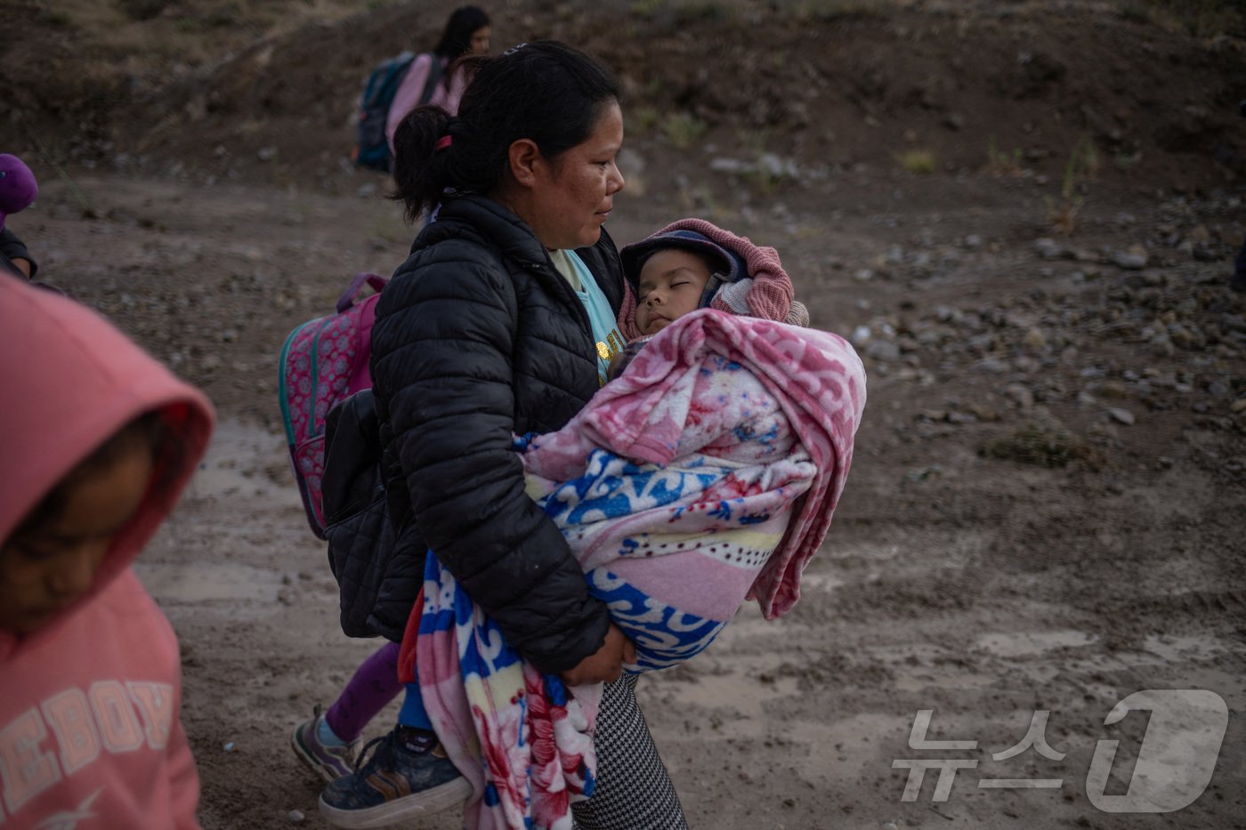 본문 이미지 - 멕시코에서 온 이민자 여성이 25일(현지시간) 딸을 안은 채 멕시코로부터 미국으로 국경을 넘고 있다. 2024.06.25 ⓒ 로이터=뉴스1 ⓒ News1 임여익 기자