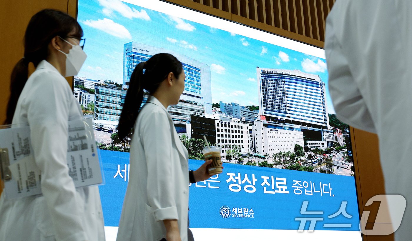 본문 이미지 - 연세 세브란스 교수들이 무기한 휴진에 돌입한 27일 오전 서울 서대문구 세브란스 병원 전광판에 표시 중인 '세브란스병원은 정상 진료 중입니다'안내 문구 앞으로 의료진이 지나가고 있다. 2024.6.27/뉴스1 ⓒ News1 장수영 기자