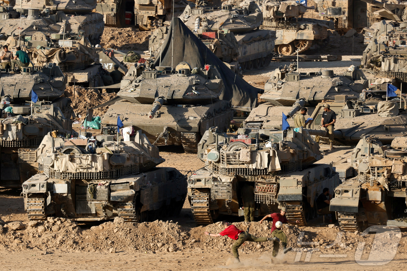 (가자-이스라엘 국경 로이터=뉴스1) 정지윤 기자 = 이스라엘과 가자지구의 접경 지역에 이스라엘군의 탱크가 여러 대 놓여있는 가운데 두 이스라엘군 병사가 축구를 하고 있다. 202 …