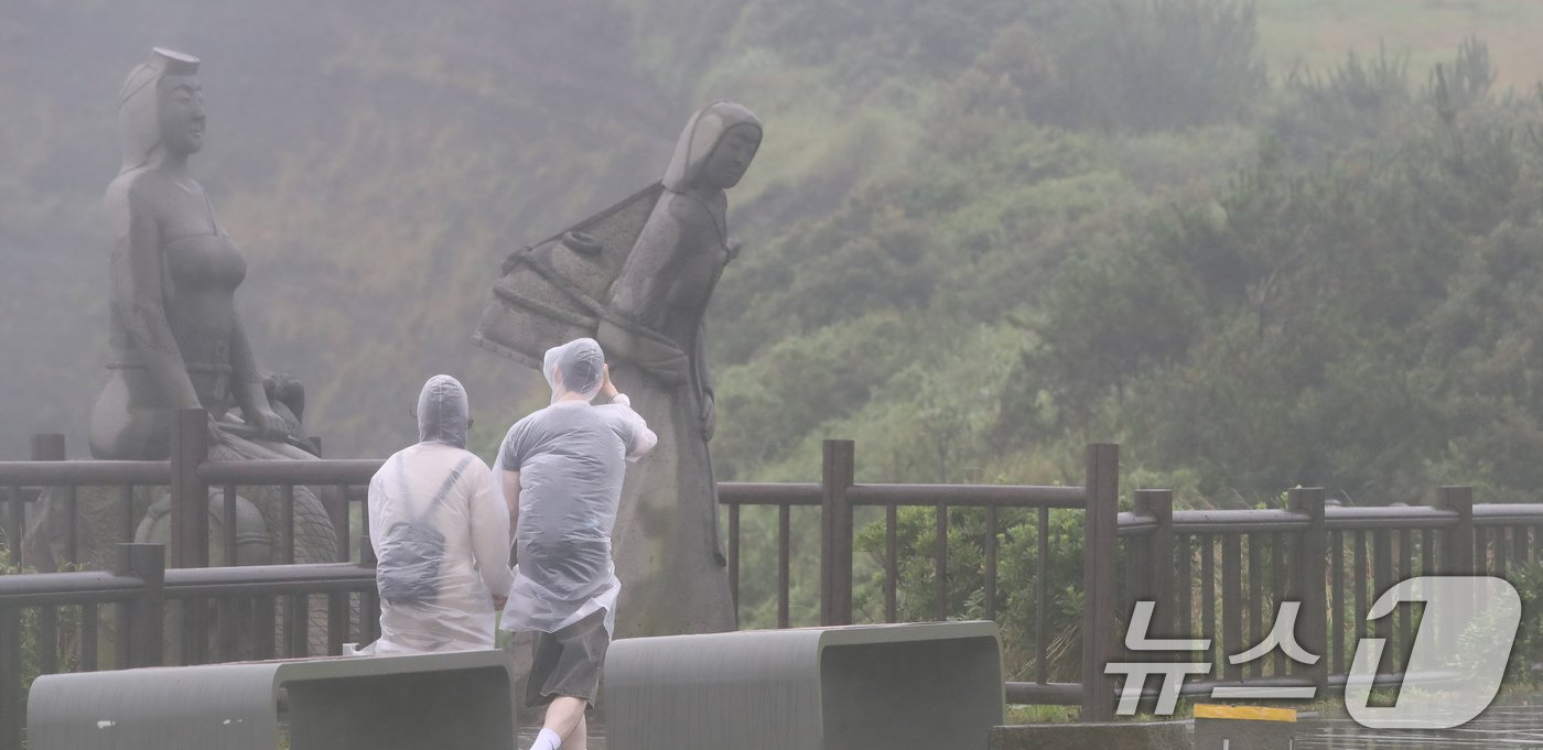 제주에 이틀째 거센 장맛비와 함께 강풍이 몰아치는 30일 오전 서귀포시 대정읍 송악산 둘레길에서 관광객들이 우비를 입고 이동하고 있다. 2024.6.30/뉴스1 ⓒ News1 오현지 기자