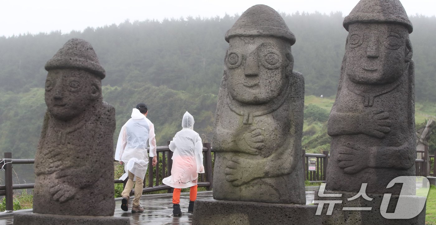 본문 이미지 - 제주에 이틀째 거센 장맛비와 함께 강풍이 몰아치는 30일 오전 서귀포시 대정읍 송악산 둘레길에서 관광객들이 우비를 입고 이동하고 있다. 2024.6.30/뉴스1 ⓒ News1 오현지 기자
