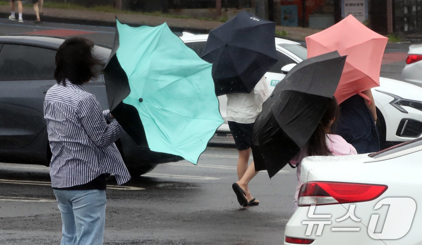 본문 이미지 - 제주에 이틀째 거센 장맛비와 함께 강풍이 몰아치는 30일 오전 서귀포시 대정읍 송악산 둘레길에서 한 관광객이 쓴 우산이 뒤집히고 있다. 2024.6.30/뉴스1 ⓒ News1 오현지 기자