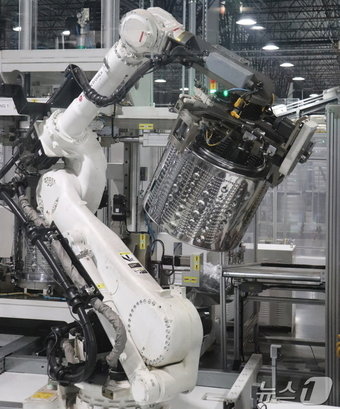 본문 이미지 - LG전자 미국 테네시 공장에서 로봇이 사람을 대신해 세탁통을 들어올리고 있는 모습. 사진은 LG전자 제공.