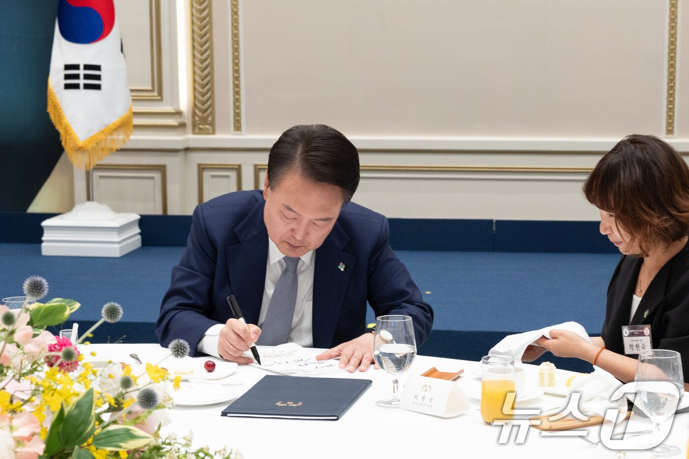 본문 이미지 - 윤석열 대통령이 6일 청와대 영빈관에서 열린 국가유공자 및 보훈가족 초청 오찬에서 참석자 이름이 수놓인 냅킨에 서명을 하고 있다. (대통령실 제공) 2024.6.6/뉴스1 ⓒ News1 송원영 기자