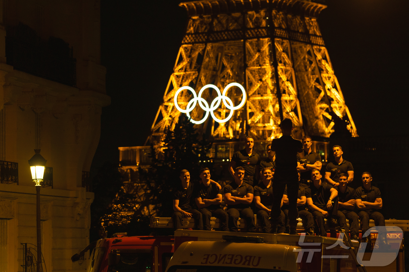 (파리=뉴스1) 이준성 기자 = 8일(현지시간) 프랑스 파리 에펠탑이 보이는 한 주택가에서 프랑스 소방대원들이 대형 오륜 조형물이 설치된 에펠탑을 배경으로 기념 촬영을 하고 있다. …