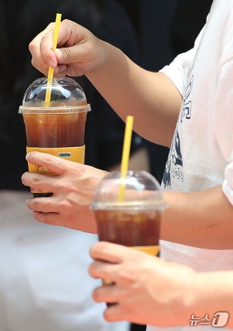 본문 이미지 - 서울 시내에 위치한 저가 브랜드 커피 매장 앞에서 시민들이 커피를 들고 이동하고 있다. 2024.7.1/뉴스1 ⓒ News1 임세영 기자