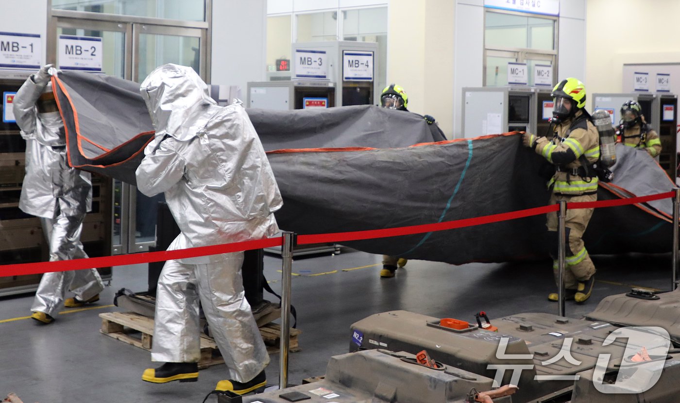 본문 이미지 - 지난달 제주시 아라동 전기차배터리산업화센터에서 민관 합동으로 열린 화재 대응 훈련에서 소방관들이 전기차 리튬 배터리에 질식소화포를 덮고 있다.ⓒ News1 고동명 기자