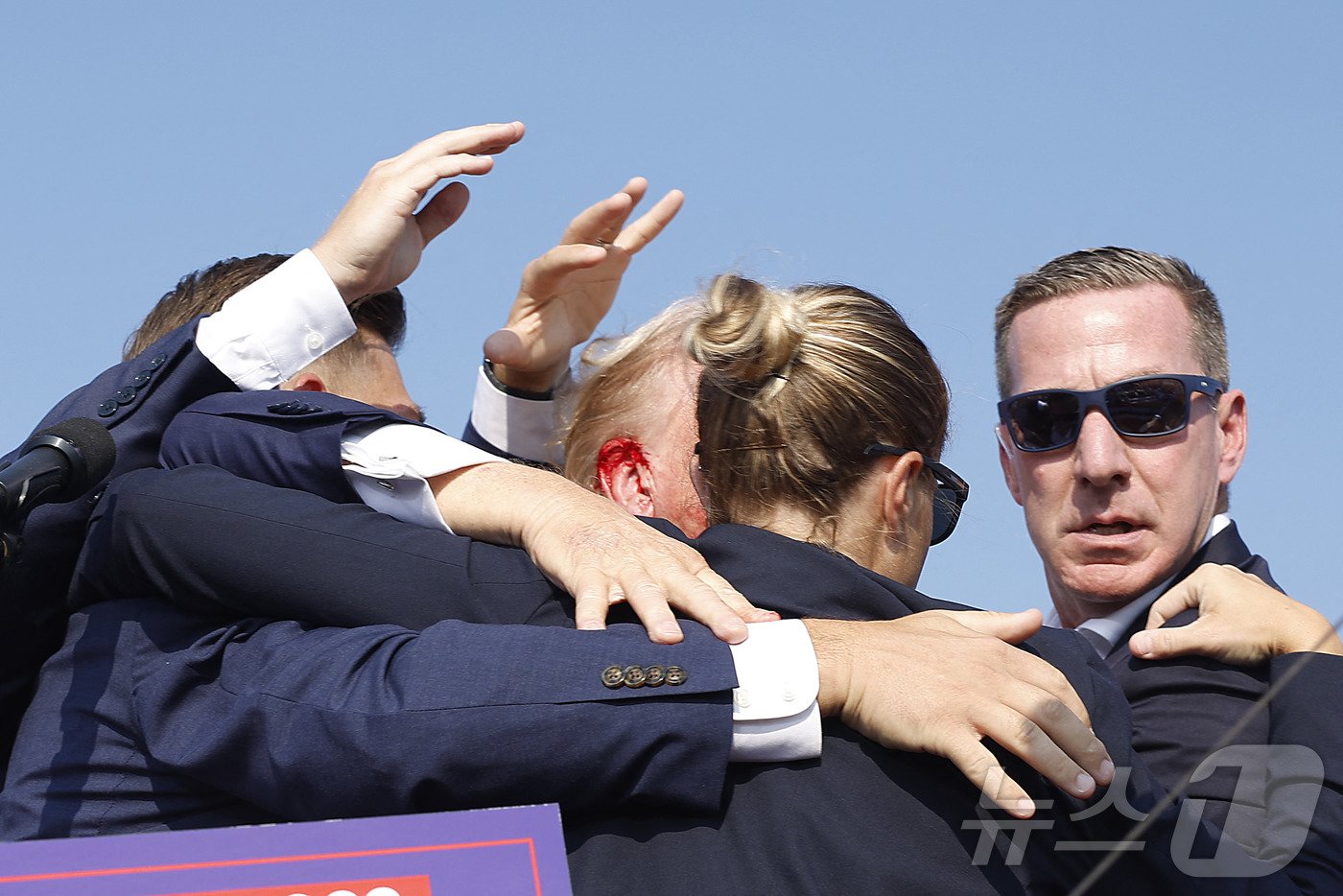 본문 이미지 - 도널드 트럼프 전 미국 대통령이 13일 (현지시간) 펜실베이니아주 버틀러에서 열린 선거 집회서 유세를 하던 중 총격 사건이 발생해 귀에  피가 낭자한 가운데, 경호원들이 긴급하게 대피를 시키고 있다. 2024.07.14 ⓒ AFP=뉴스1 ⓒ News1 우동명 기자