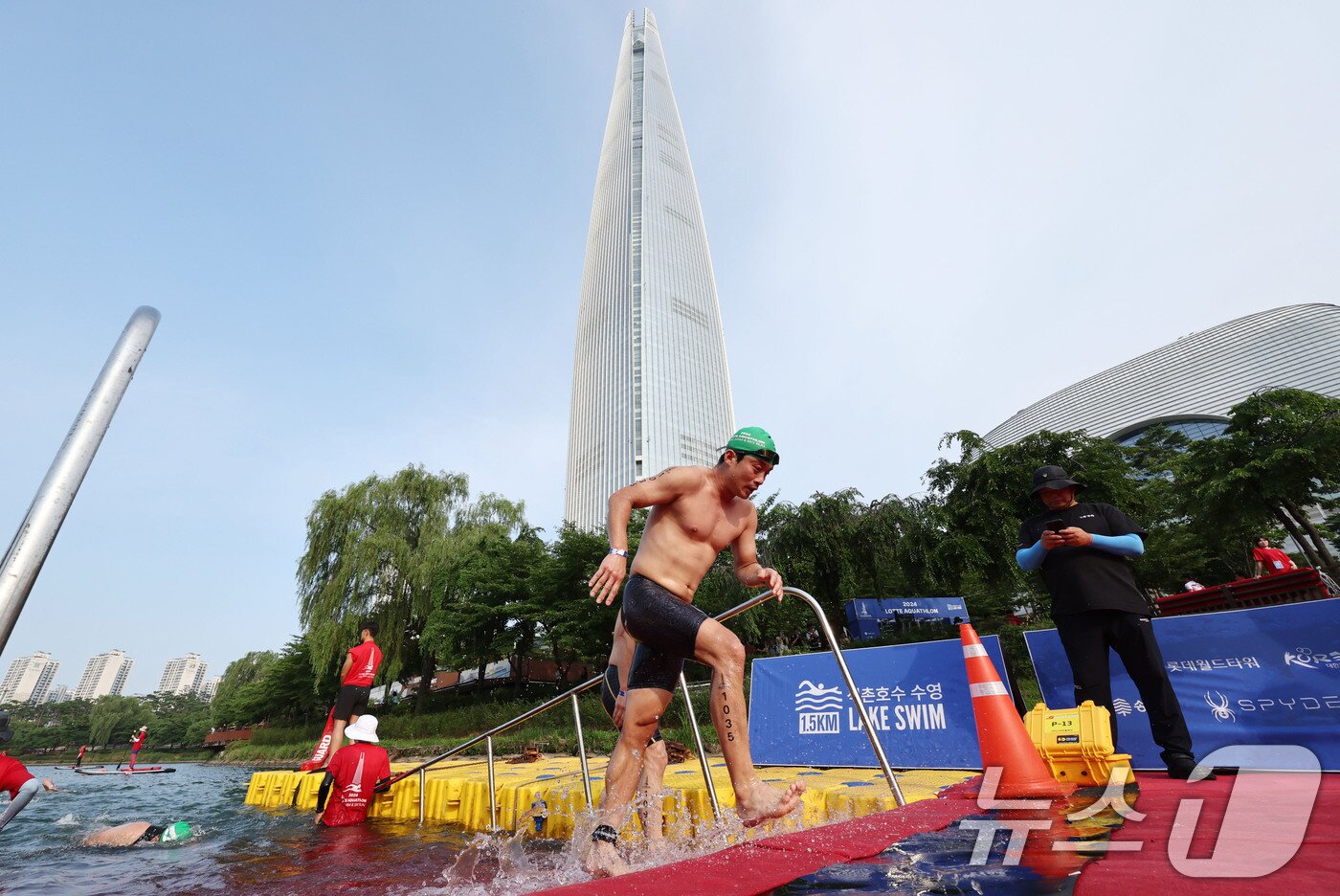 본문 이미지 - 14일 오전 서울 송파구 롯데월드타워 일대에서 열린 '2024 롯데 아쿠아슬론'에 출전한 참가자들이 석촌호수에서 수영을 마치고 수직마라톤을 향해 달리고 있다.  (공동취재) 2024.7.14/뉴스1 ⓒ News1 임세영 기자