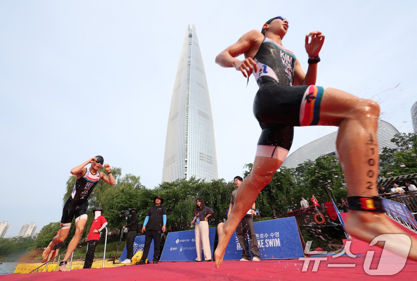 본문 이미지 - 14일 오전 서울 송파구 롯데월드타워 일대에서 열린 '2024 롯데 아쿠아슬론'에 출전한 참가자들이 석촌호수에서 수영을 마치고 수직마라톤을 향해 달리고 있다.  (공동취재) 2024.7.14/뉴스1 ⓒ News1 임세영 기자