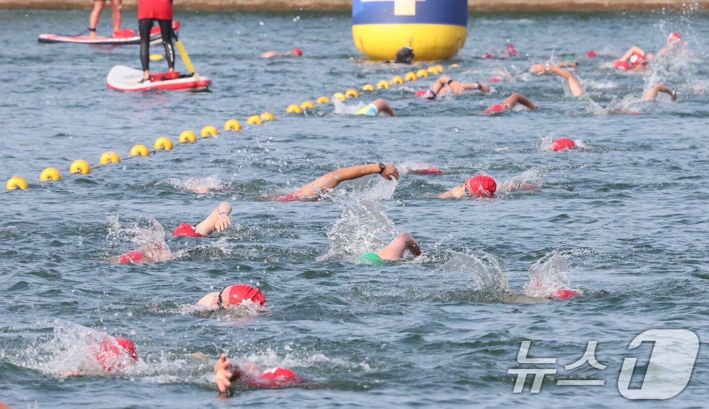 본문 이미지 - 14일 오전 서울 송파구 롯데월드타워 일대에서 열린 '2024 롯데 아쿠아슬론'에 출전한 참가자들이 석촌호수에서 수영을 하고 있다.  (공동취재) 2024.7.14/뉴스1 ⓒ News1 임세영 기자