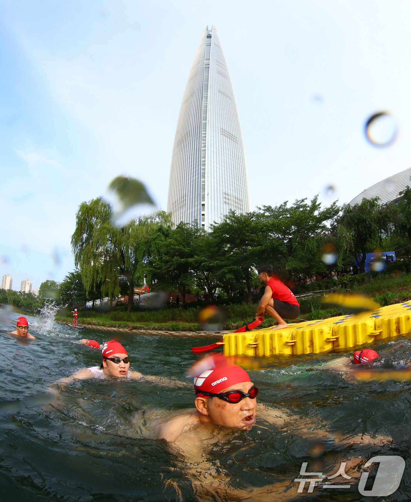 본문 이미지 - 14일 오전 서울 송파구 롯데월드타워 일대에서 열린 '2024 롯데 아쿠아슬론'에 출전한 참가자들이 석촌호수에서 수영을 하고 있다. (공동취재) 2024.7.14/뉴스1 ⓒ News1 임세영 기자