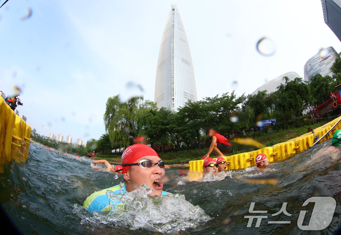 본문 이미지 - 14일 오전 서울 송파구 롯데월드타워 일대에서 열린 '2024 롯데 아쿠아슬론'에 출전한 참가자들이 석촌호수에서 수영을 하고 있다. (공동취재) 2024.7.14/뉴스1 ⓒ News1 임세영 기자