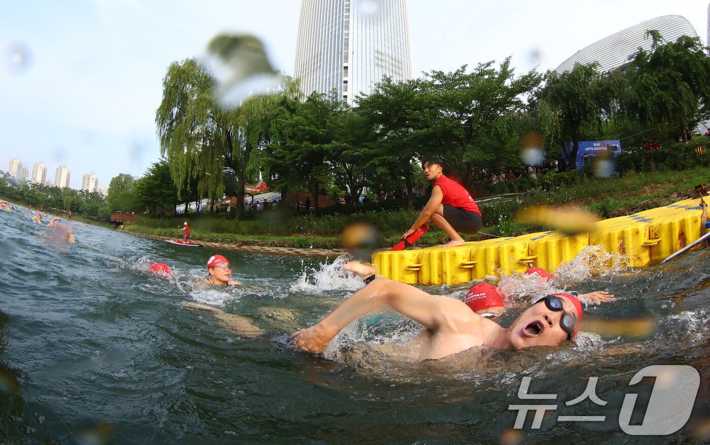본문 이미지 - 14일 오전 서울 송파구 롯데월드타워 일대에서 열린 '2024 롯데 아쿠아슬론'에 출전한 참가자들이 석촌호수에서 수영을 하고 있다.  (공동취재) 2024.7.14/뉴스1 ⓒ News1 임세영 기자