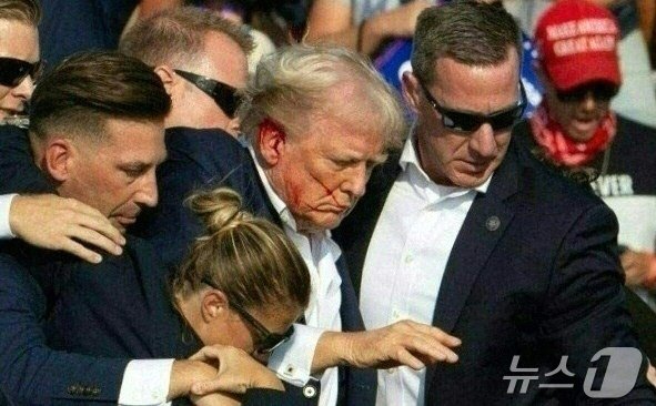 본문 이미지 - 도널드 트럼프 전 미국 대통령이 13일 (현지시간) 펜실베이니아주 버틀러에서 열린 선거 집회서 유세를 하던 중 총격 사건이 발생해 얼굴에 핏자국을 묻은 가운데 경호원들과 긴급하게 대피를 하고 있다. 2024.07.14 ⓒ AFP=뉴스1 ⓒ News1 우동명 기자
