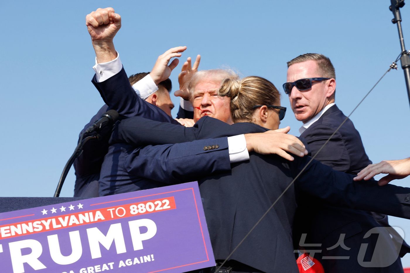 본문 이미지 - 13일(현지시간) 미국 공화당 대선후보인 도널드 트럼프 전 대통령이 펜실베이니아 버틀러에서 연설 도중 오른쪽 귀에 총상을 입고 무대 밖으로 대피하고 있다. 2024.07.15. ⓒ AFP=뉴스1 ⓒ News1 장시온 기자