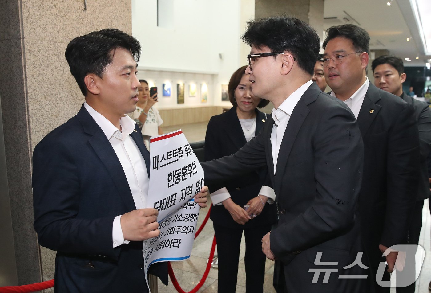 본문 이미지 - 한동훈 국민의힘 당대표 후보가 18일 오후 서울 중구 서울시의회에서 열린 국민의힘 서울시의회 의원간담회 회의장 앞에서 &#39;패스트트랙 투쟁 폄훼 한동훈 후보 당대표 자격 없다&#39;가 적힌 피켓을 든 이희원 서울시의원&#40;국민의힘&#41;과 이야기를 나누고 있다. 2024.7.18/뉴스1 ⓒ News1 임세영 기자