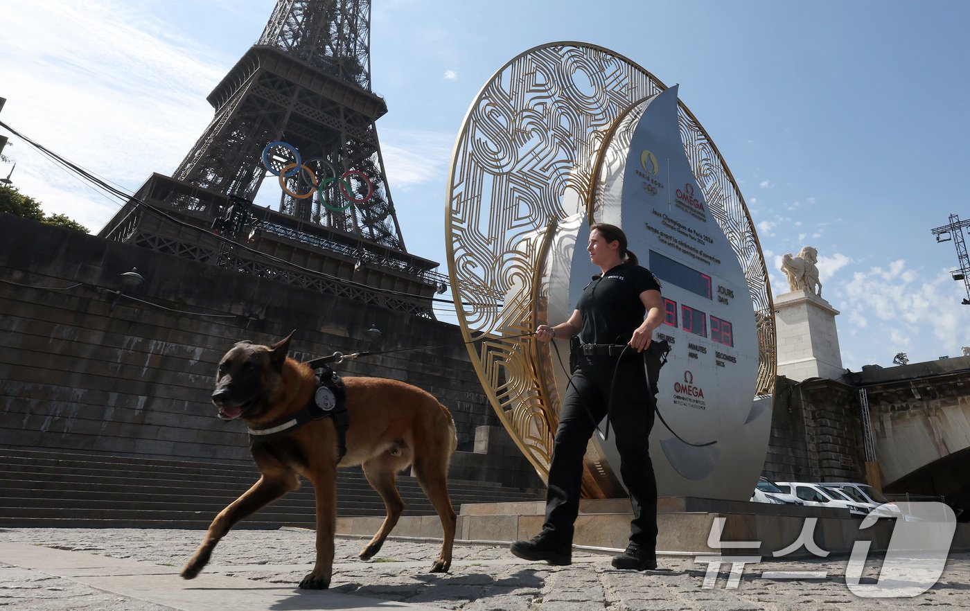 본문 이미지 - 파리올림픽 개막을 일주일 앞둔 19일 오후&#40;한국시간&#41; 프랑스 파리의 에펠탑 아래 설치된 타임키퍼 앞으로 경찰 인력이 오가고 있다. 2024.7.19/뉴스1 ⓒ News1 이동해 기자