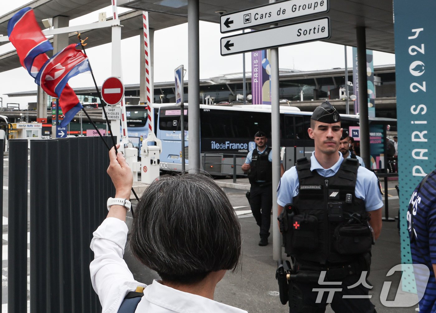 본문 이미지 - 조선·프랑스 친선 환여단이 21일 오후(한국시간) 프랑스 파리 샤를 드골 공항을 통해 입국하는 북한 선수단을 환영하고 있다. 2024.7.21/뉴스1 ⓒ News1 박정호 기자
