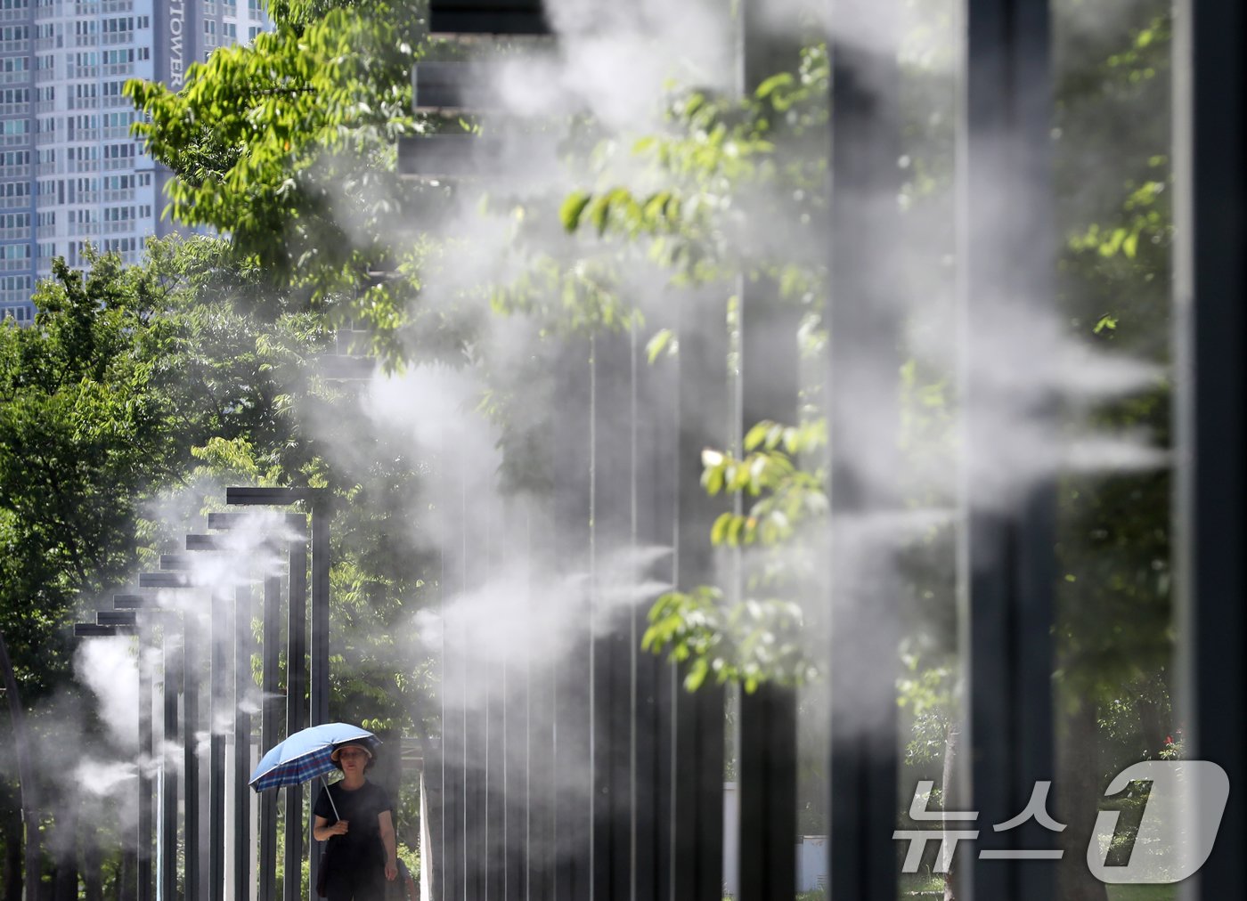 본문 이미지 - 중복 더위가 기승을 부린 25일 오후 부산 부산진구 부산시민공원에서 양산을 쓴 시민이 쿨링포그를 맞으며 이동하고 있다. 2024.7.25/뉴스1 ⓒ News1 윤일지 기자