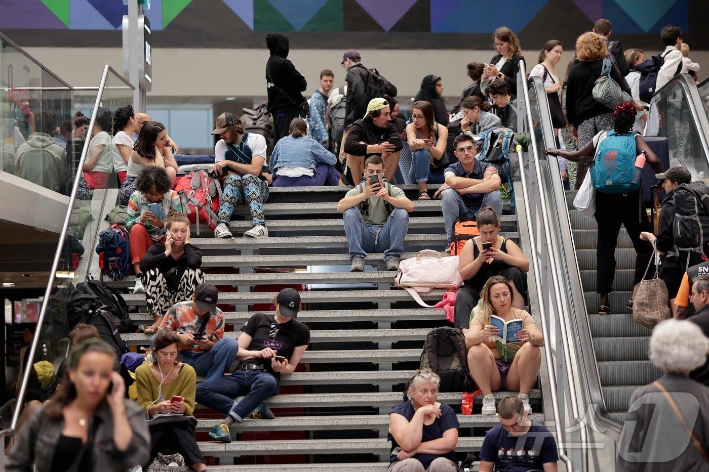 본문 이미지 - 26일 파리 올림픽 개막식을 불과 몇 시간 앞두고 테제베(TGV) 고속철에서 방화 등 '악의적 행동'이 일어나 교통망이 마비되는 사태가 발생했다. 프랑스 철도청(SNCF)은 이날 프랑스 고속철로 네트워크가 방화 공격을 포함한 '악의적인 행동'으로 인해 운영이 중단됐다고 밝혔다. 영향을 받은 노선은 아틀란틱 노선과 북부, 동부 노선 등인 것으로 알려졌다. SNCF는 이어 "열차들이 다른 선로로 우회하고 있지만 많은 수의 열차를 취소해야 할 것＂이라며 승객들에게 여행 일정을 연기하고 기차역에서 멀리 떨어질 것을 당부했다. 사진은 파리 게어 몽파르나스 터미널에서 오지 못하는 기차를 하염없이 기다리고 앉아 있는 승객들의 모습이다. 2024.0726 ⓒ AFP=뉴스1 ⓒ News1 권진영기자