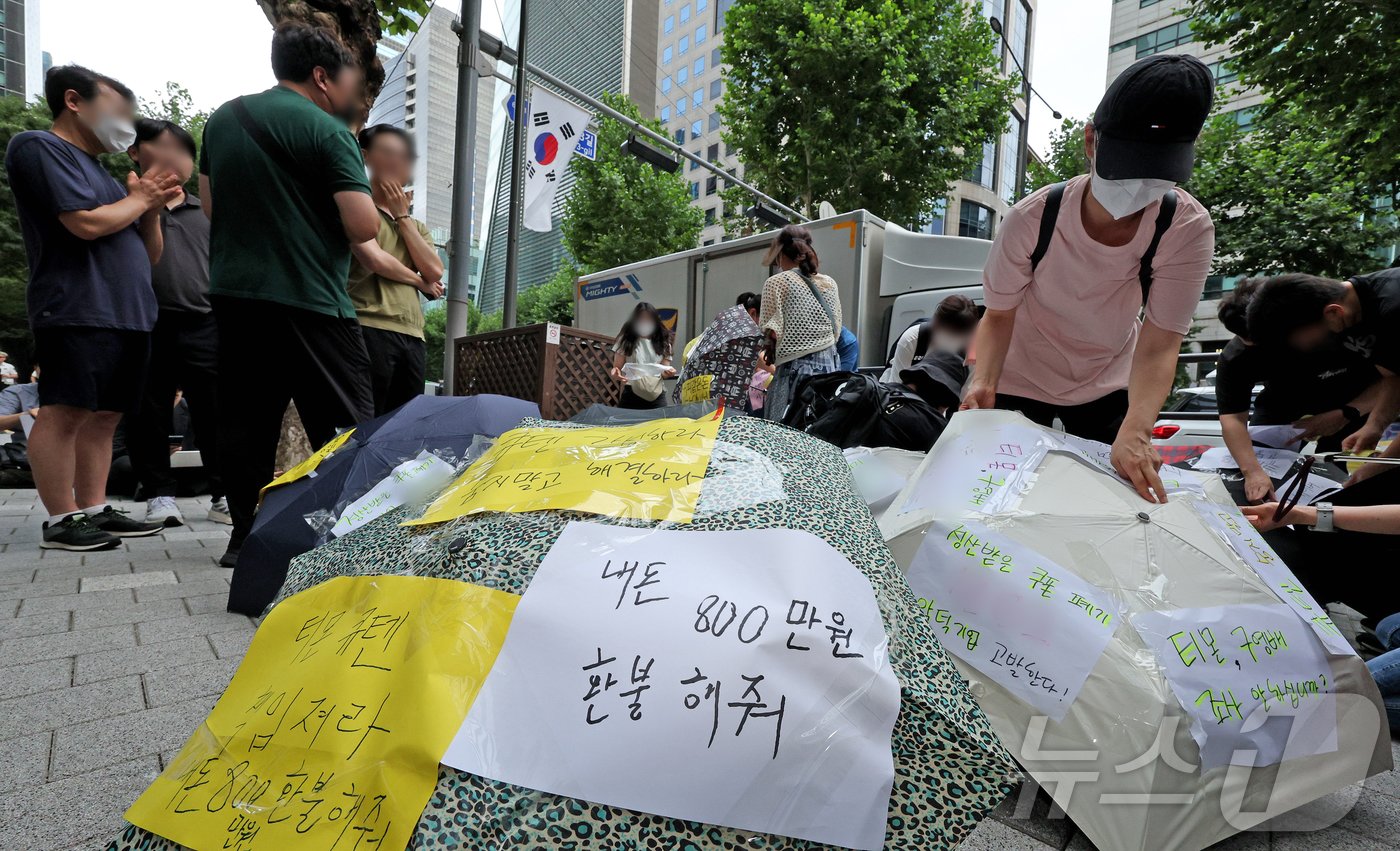 티몬과 위메프의 정산·환불 지연 사태가 지속되고 있는 28일 오후 서울 강남구 큐텐 본사 앞에서 피해자들이 사태 해결을 촉구하는 문구를 우산에 붙이며 시위를 준비하고 있다. 2024.7.28/뉴스1 ⓒ News1 장수영 기자