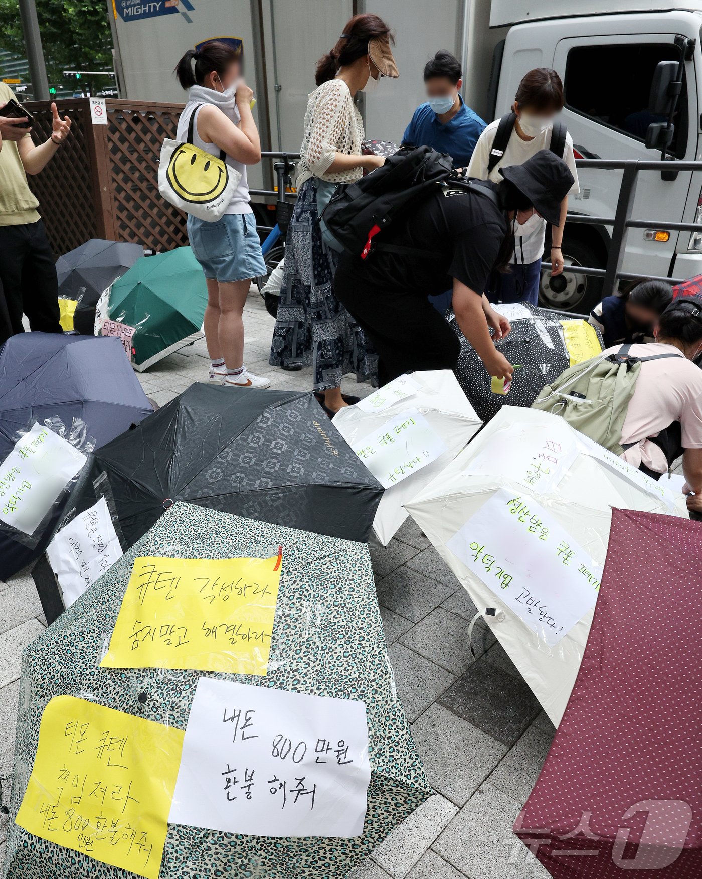 티몬과 위메프의 정산·환불 지연 사태가 지속되고 있는 28일 오후 서울 강남구 큐텐 본사 앞에서 피해자들이 사태 해결을 촉구하는 문구를 우산에 붙이며 시위를 준비하고 있다. 2024.7.28/뉴스1 ⓒ News1 장수영 기자