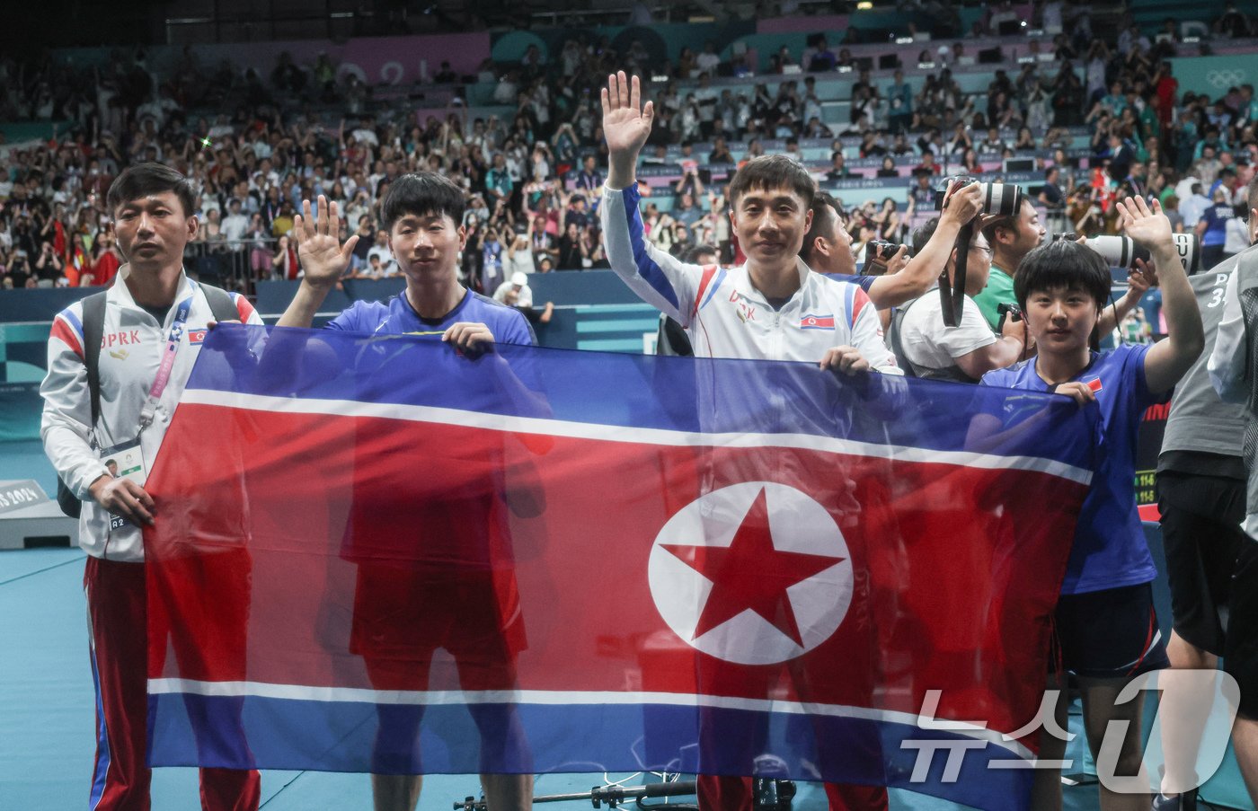 본문 이미지 - 북한 탁구 대표팀 리종식, 김금용 선수가 30일(한국시간) 프랑스 파리 사우스 파리 아레나4에서 열린 '2024 파리올림픽' 탁구 혼합복식 중국과의 결승 경기에서 은메달을 차지한 후 인공기를 들어보이고 있다. 2024.7.30/뉴스1 ⓒ News1 이동해 기자