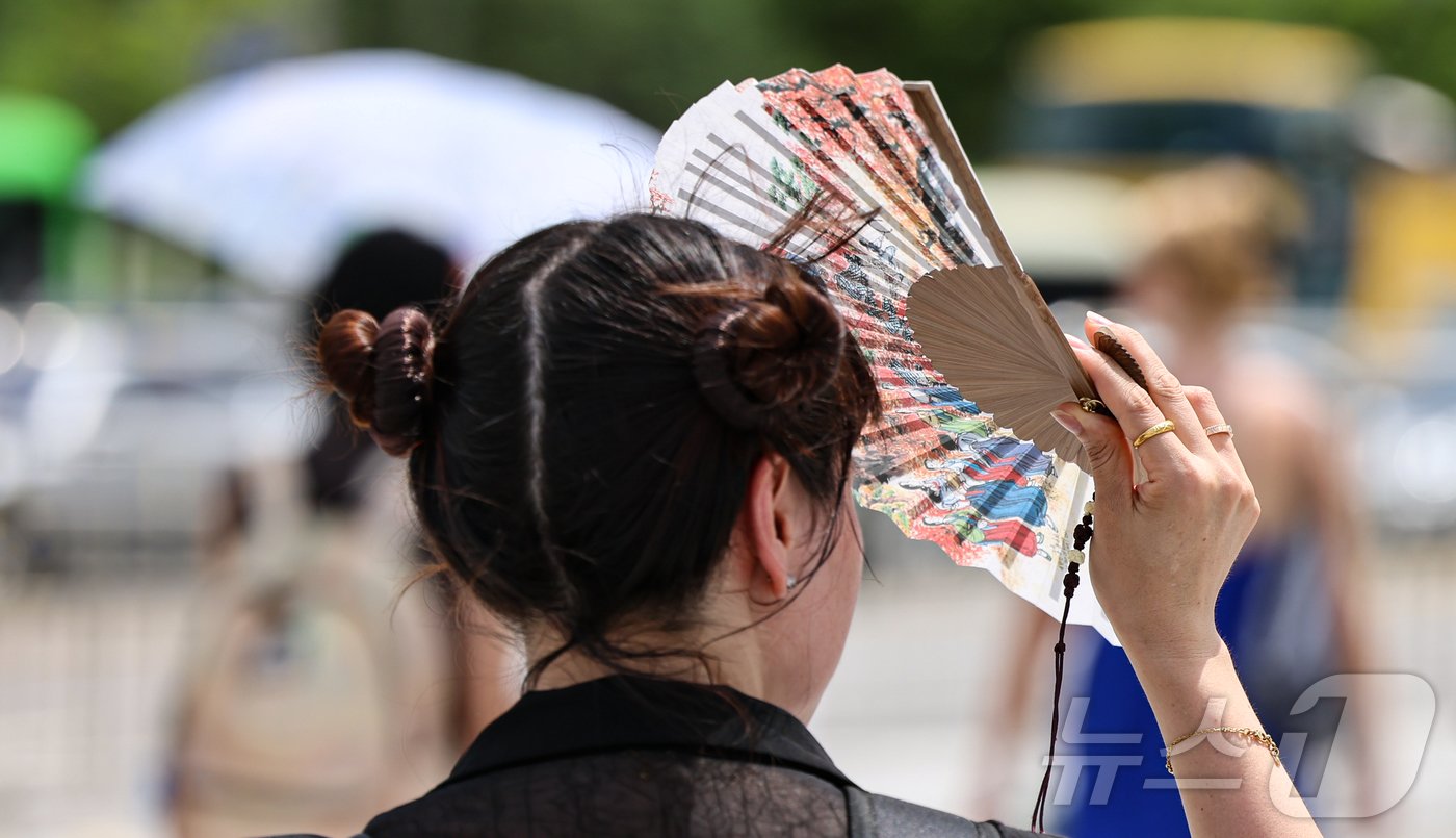 본문 이미지 - 전국 대부분 지역에 폭염특보가 내려진 지난달 31일 서울 종로구 광화문네거리 인근에서 한 시민이 부채로 햇빛을 가리며 이동하고 있다. 2024.7.31/뉴스1 ⓒ News1 김도우 기자