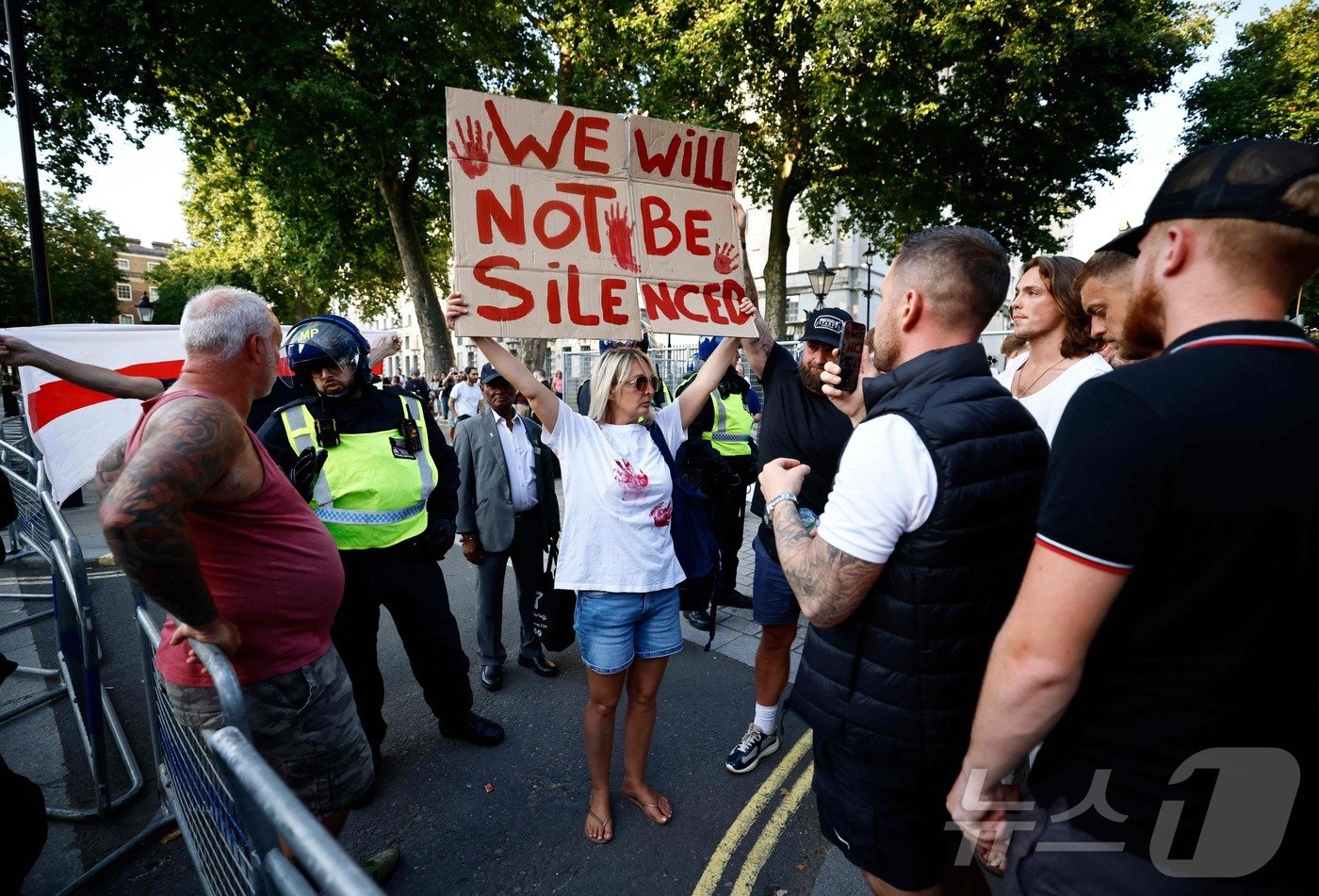 본문 이미지 - 31일(현지시간) 영국 런던 중부에 있는 다우닝 가 10번지 입구에서 벌어진 시위에서 한 시위자가 '우리는 침묵하지 않을 것이다'라고 적힌 피켓을 들고 서있다. 이날 시위는 지난 29일 영국 사우스포트에서 벌어진 흉기 난동에 대한 정부 대처 때문에 열렸다. 2024.07.31. ⓒ AFP=뉴스1 ⓒ News1 김종훈 기자