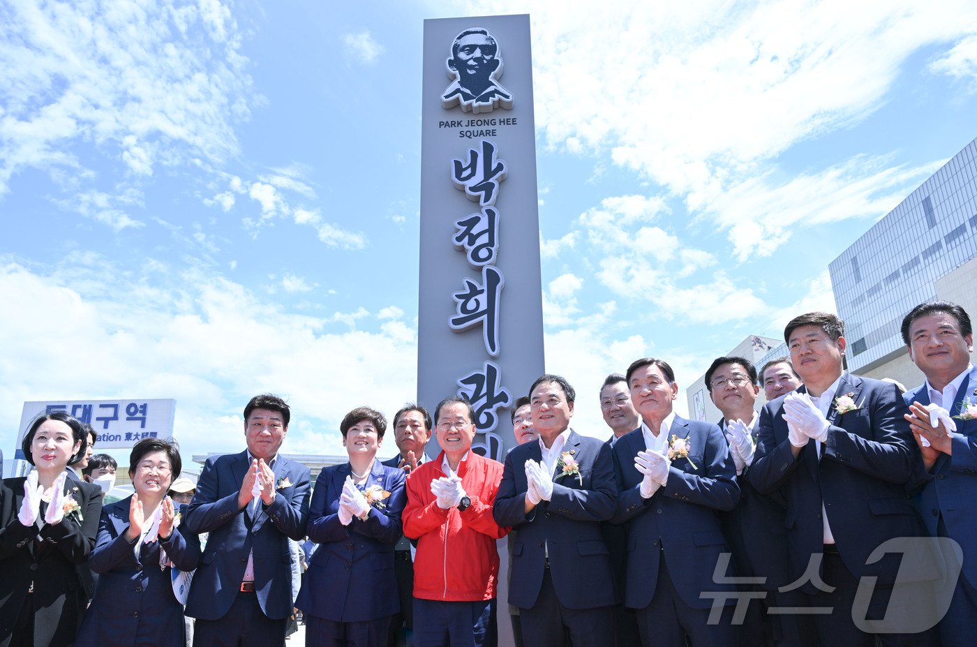 14일 동대구역 앞에서 열린 박정희 광장 표지판 제막식에서 홍준표 대구시장&#40;빨간 점퍼&#41;과 이만규 대구시의장, 강은희 대구교육감 등이 박수를 치고 있다.&#40;대구시 제공&#41;