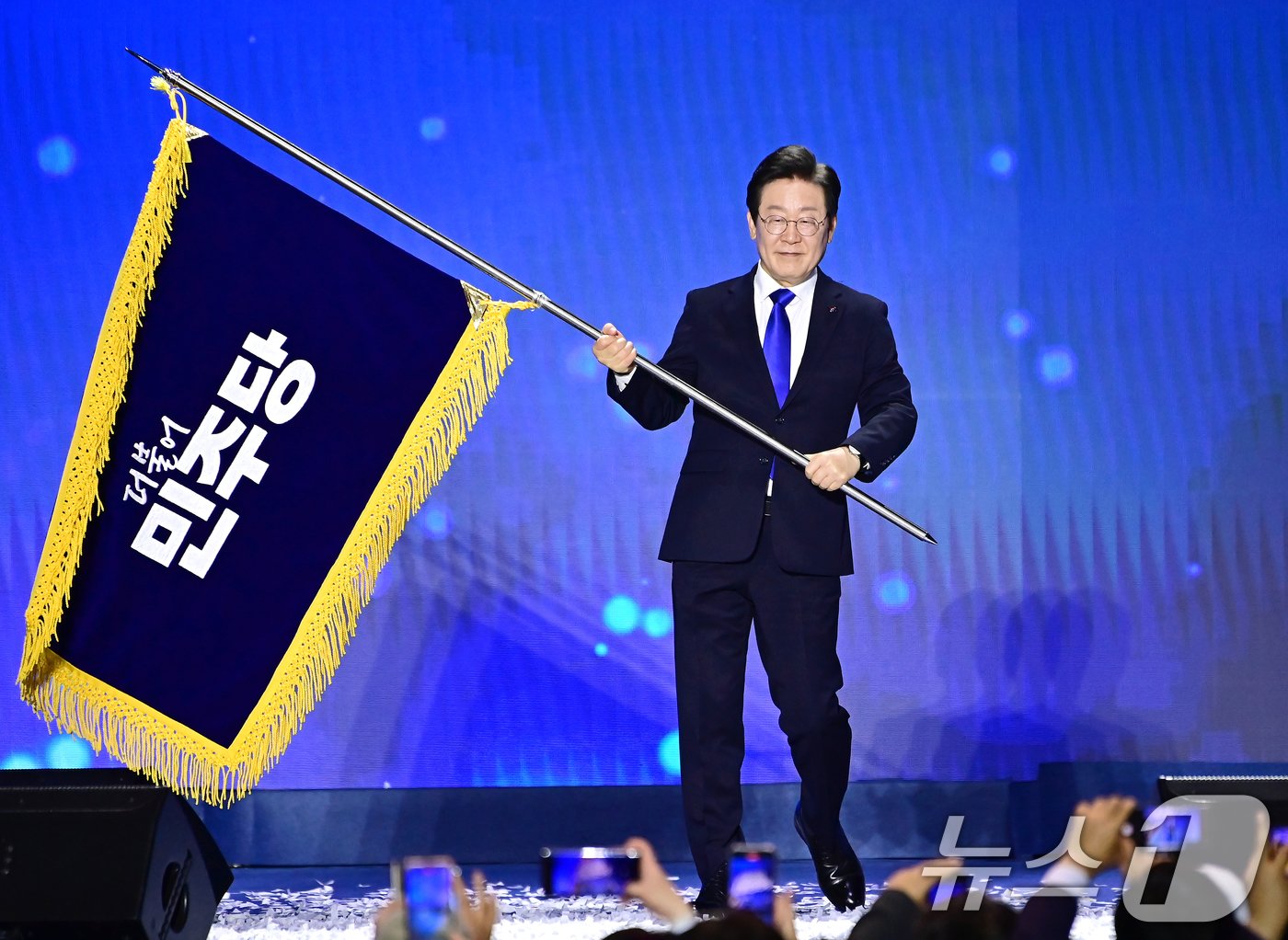 본문 이미지 - 이재명 더불어민주당 대표가 18일 오후 서울 송파구 KSPO DOME(올림픽체조경기장)에서 열린 제1차 정기전국당원대회에서 당기를 흔들고 있다. 2024.8.18/뉴스1 ⓒ News1 김민지 기자