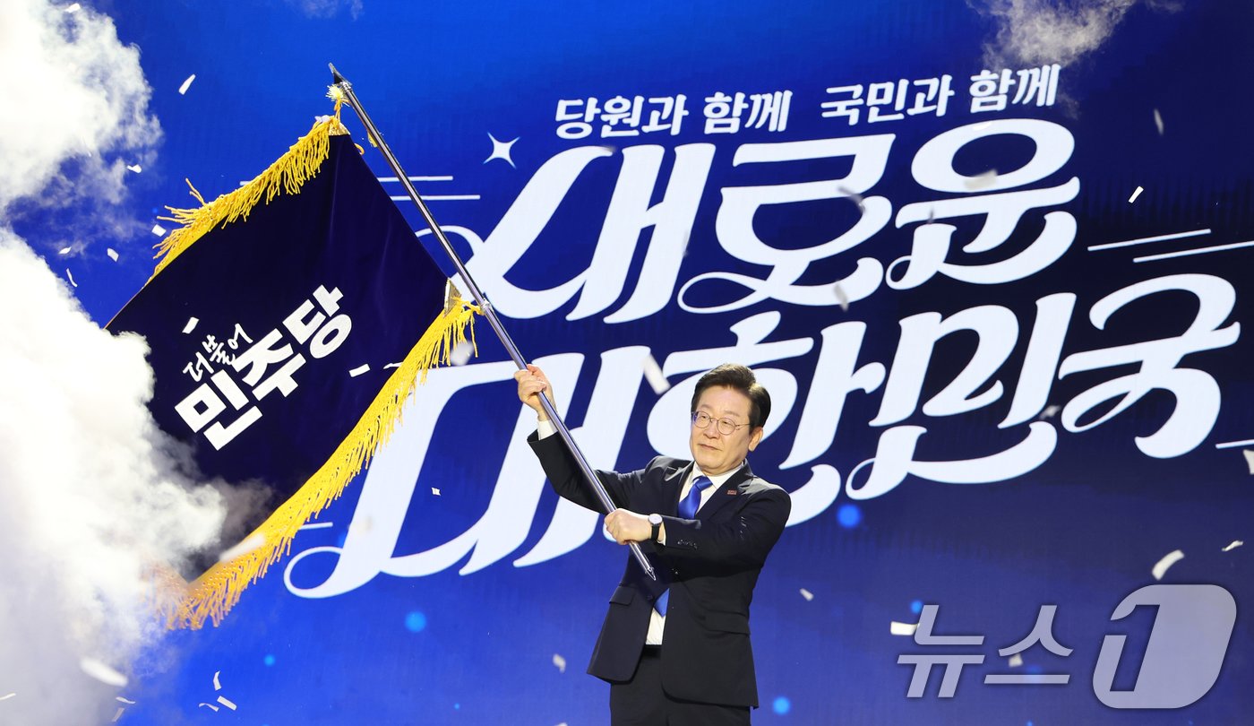 본문 이미지 - 연임에 성공한 이재명 더불어민주당 대표가 18일 서울 송파구 올림픽공원 KSPO돔에서 열린 제1차 전국당원대회에서 당기를 흔들고 있다. (공동취재)2024.8.18/뉴스1 ⓒ News1 김민지 기자
