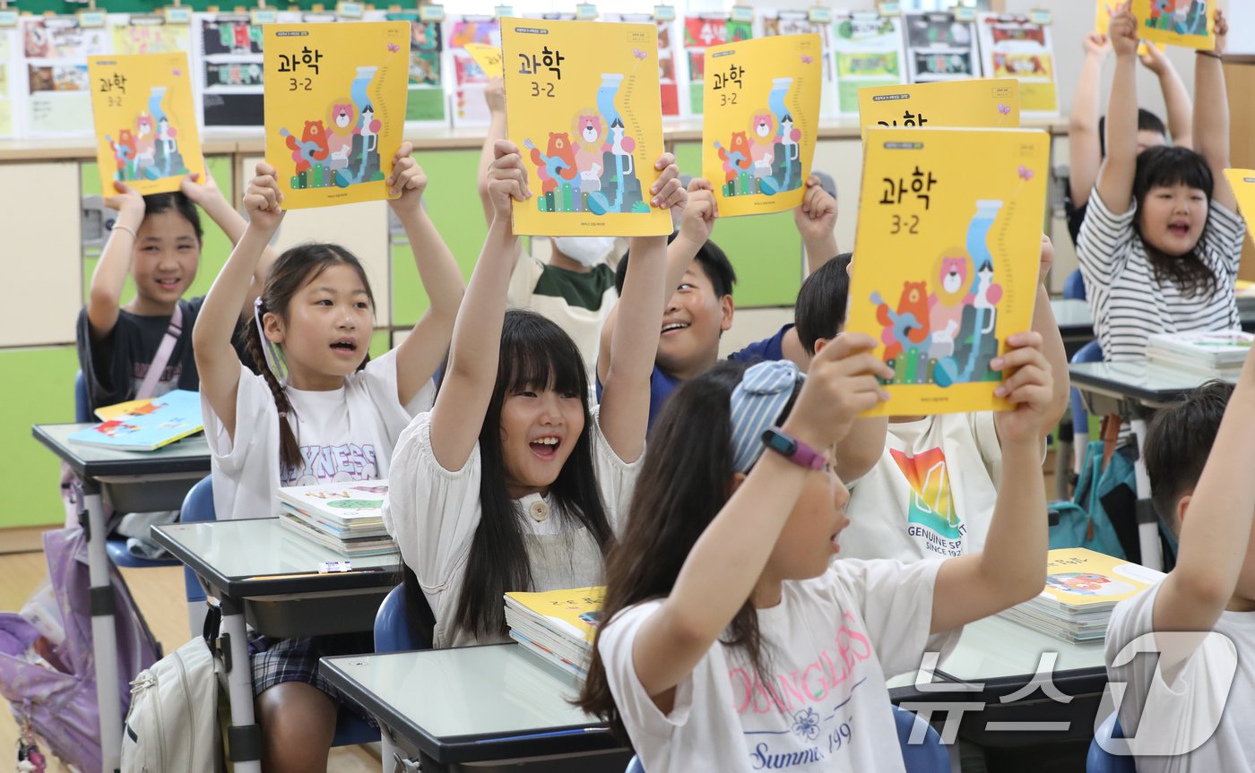 여름방학이 끝나고 개학한 19일 오전 경기 수원시 영통구 망포초등학교에서 3학년 6반 학생들이 새로 받은 2학기 교과서를 들어보이고 있다. 2024.8.19/뉴스1 ⓒ News1 김영운 기자